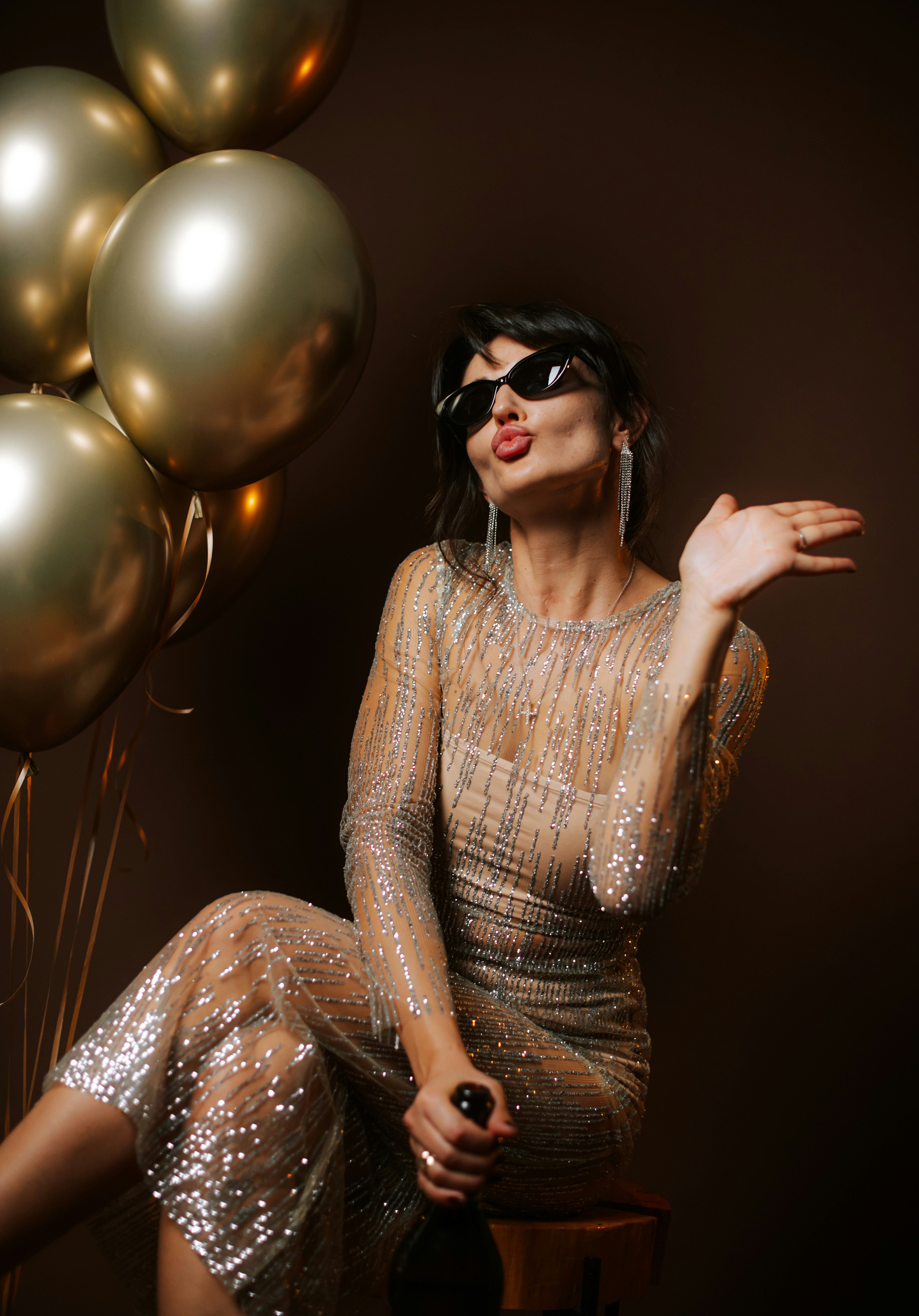 Woman in sparkly dress and sunglasses with balloons
