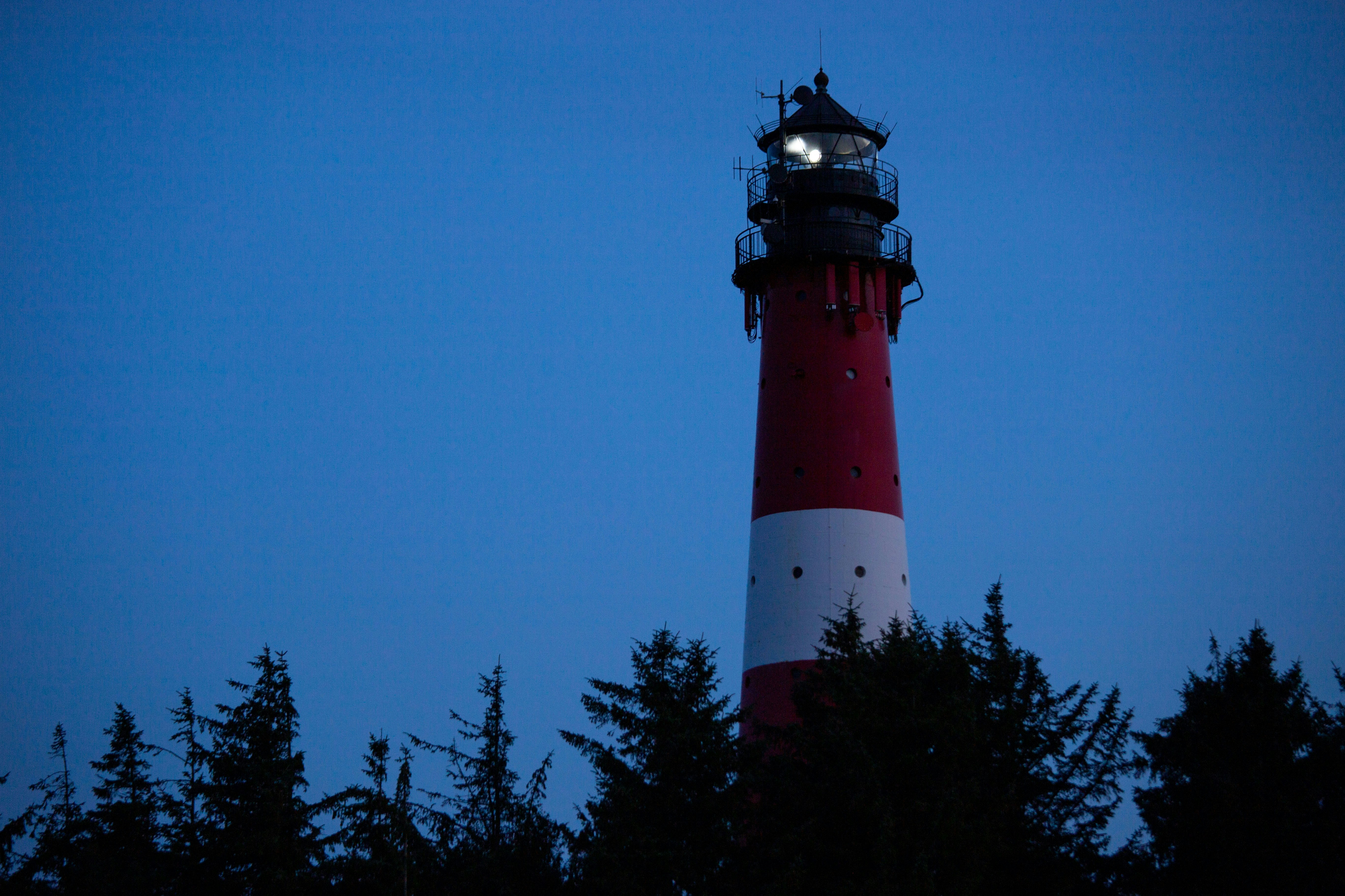 Red and white lighthouse against a dark blue sky