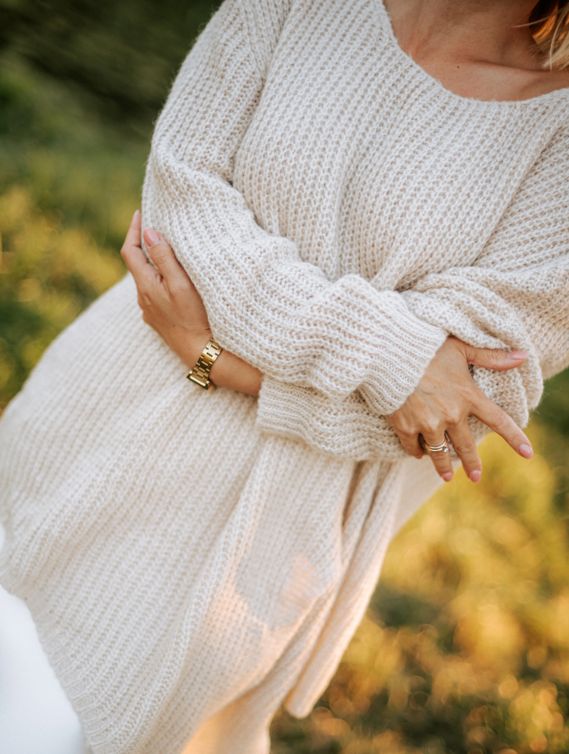 Woman in a cozy cream sweater with jewelry.