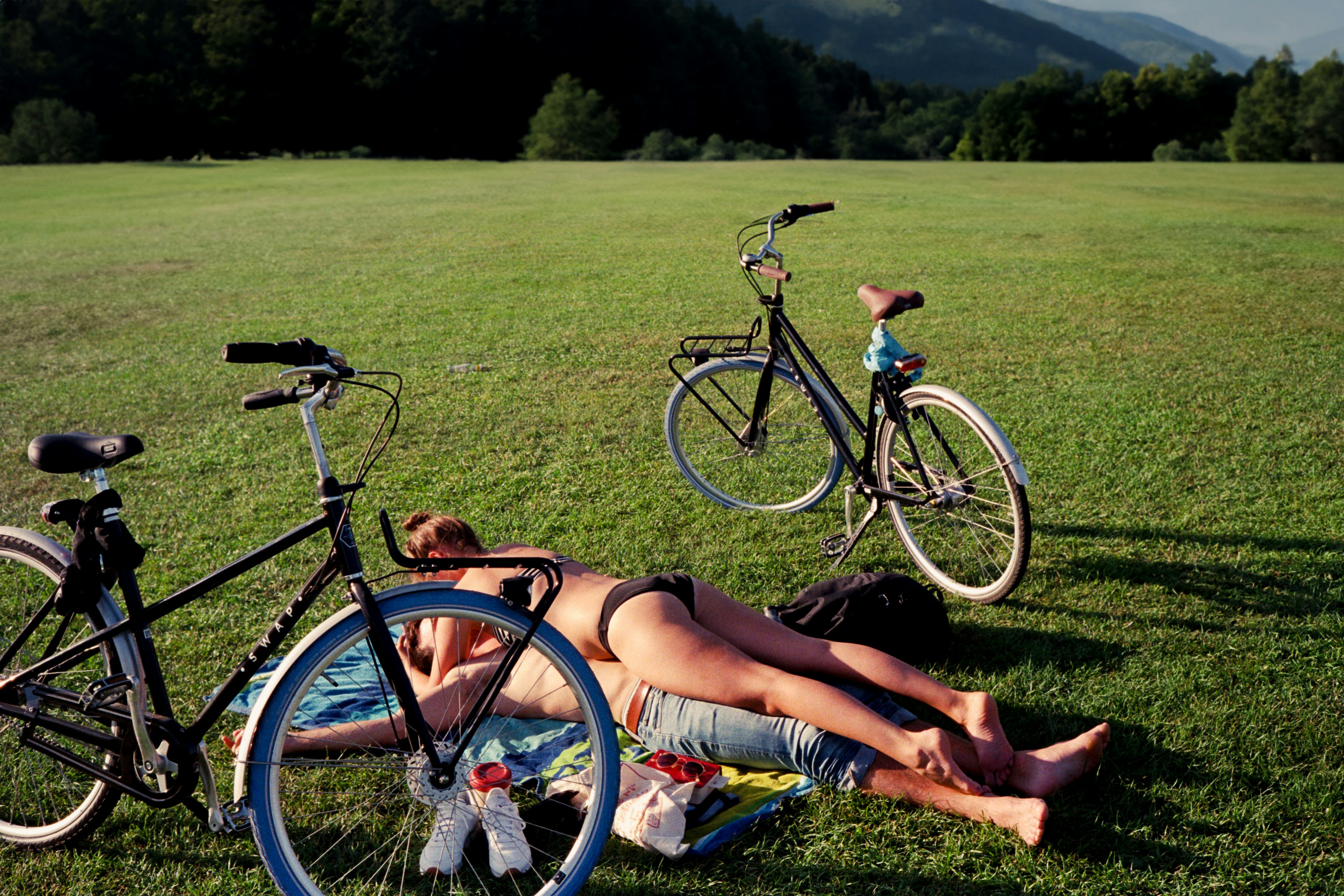 A couple relaxing on the grass with their bicycles on a warm Munich summer afternoon
