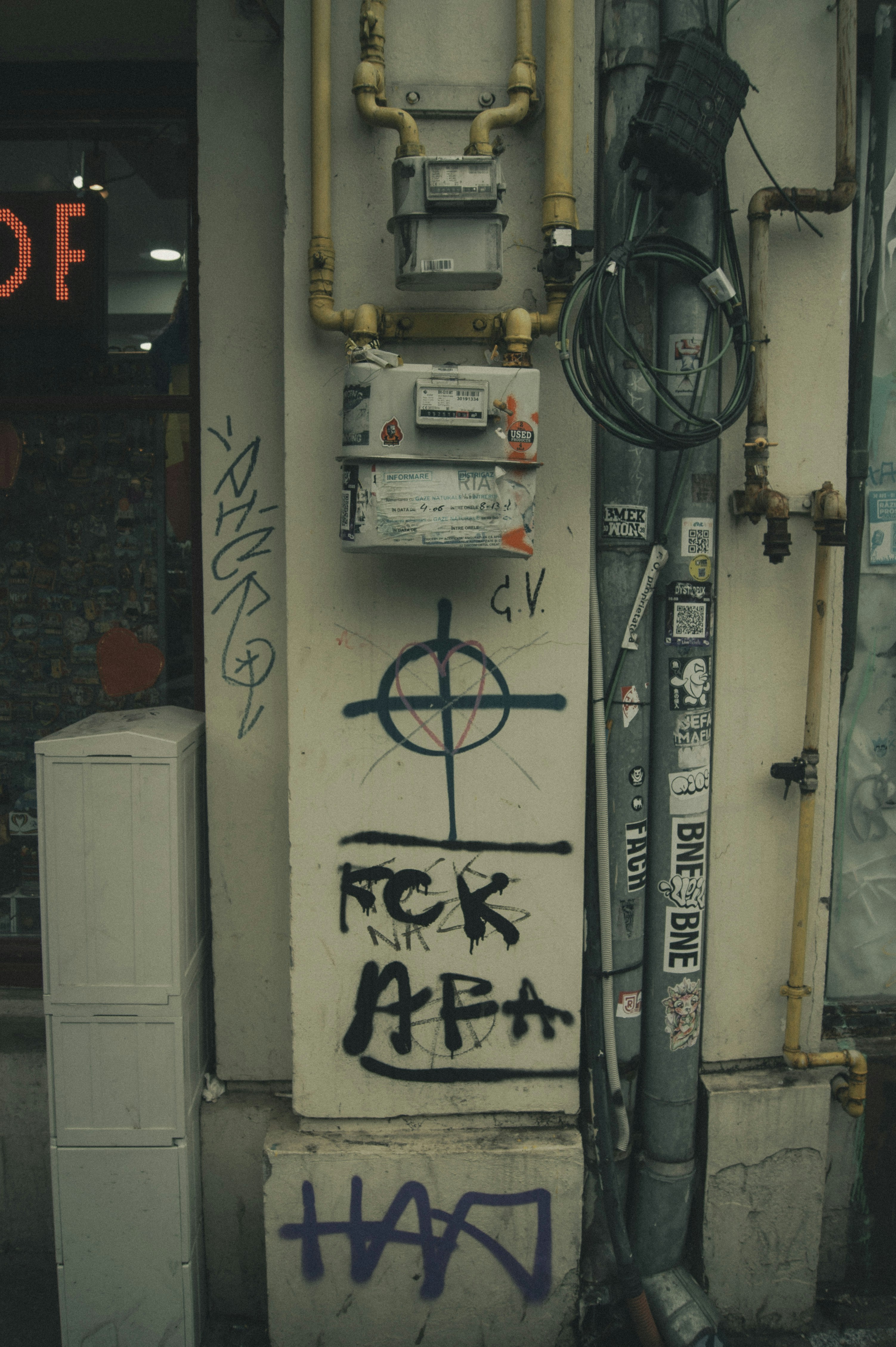 Graffiti on a building wall with pipes and meters
