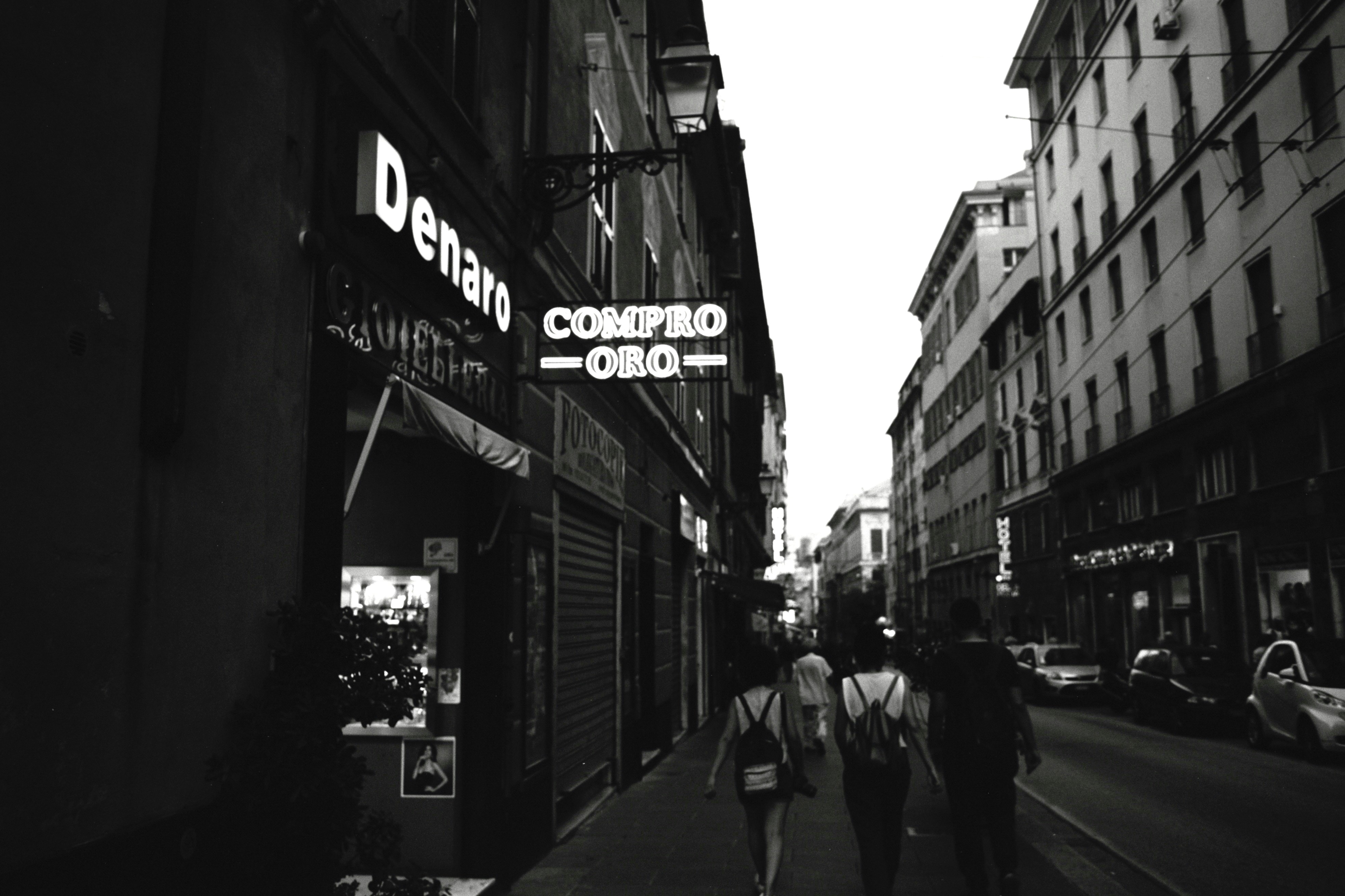 People walk down a street with shops and buildings.