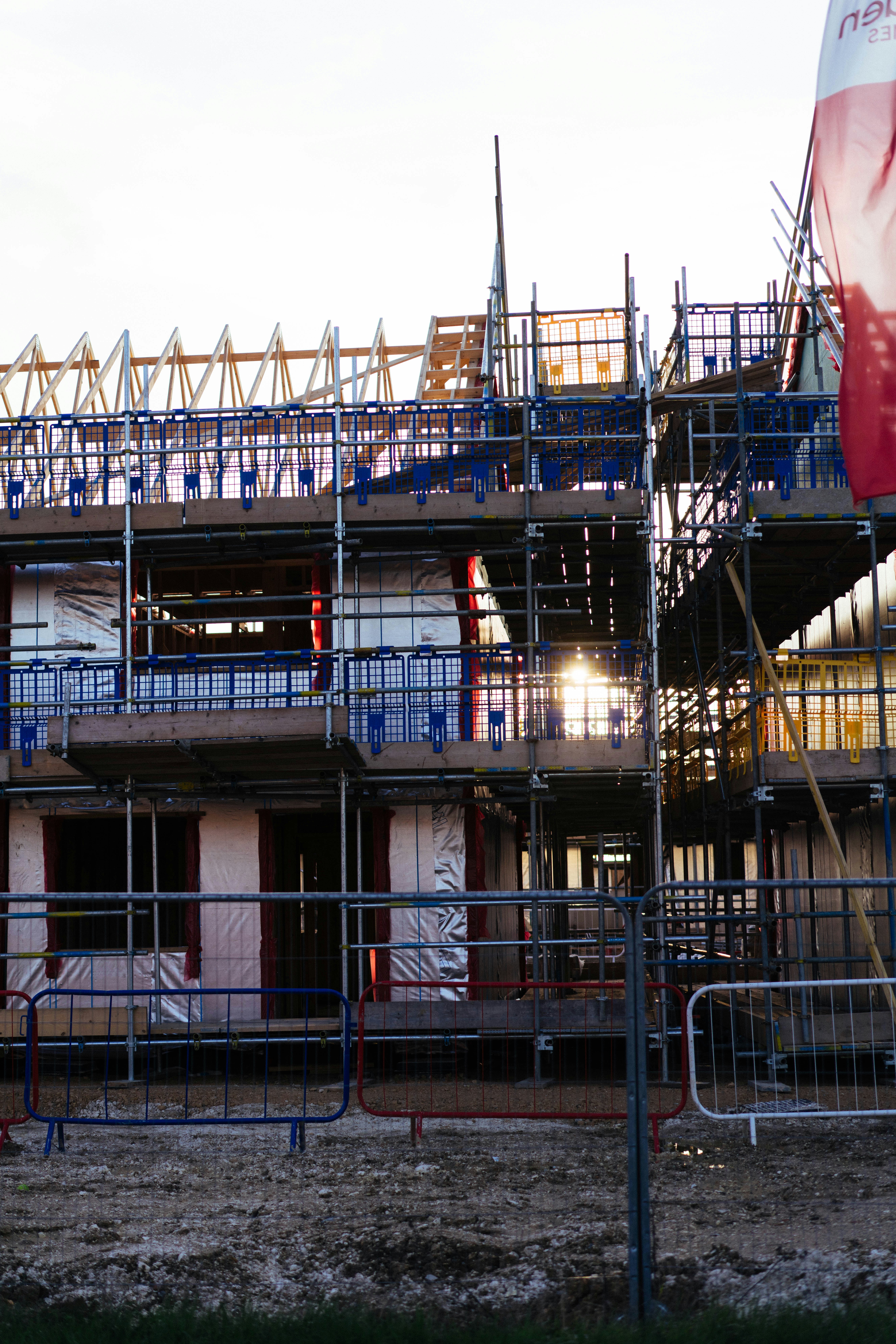 Bâtiment en construction avec échafaudage et lumière du soleil.