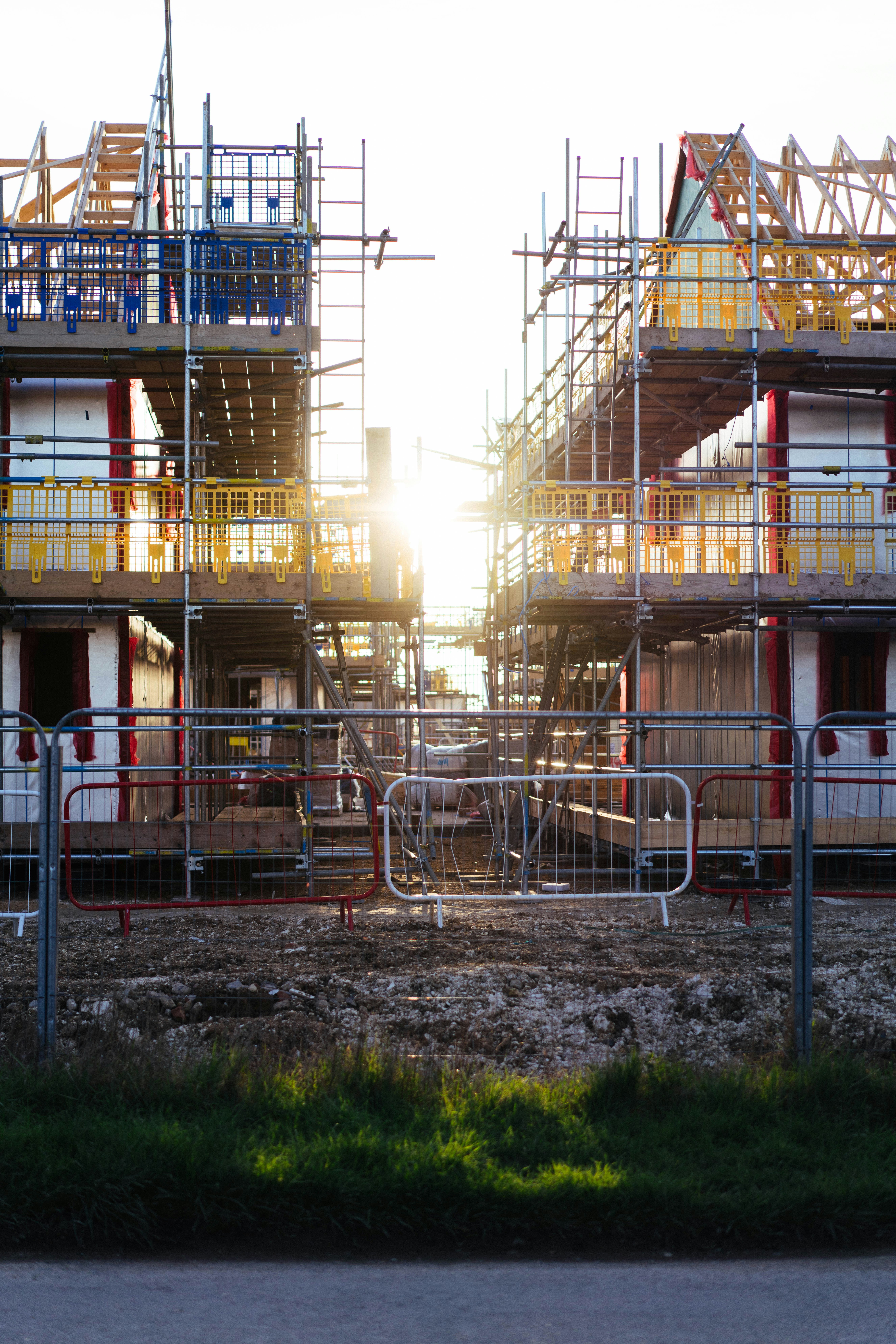 Deux maisons en construction avec échafaudages et soleil.