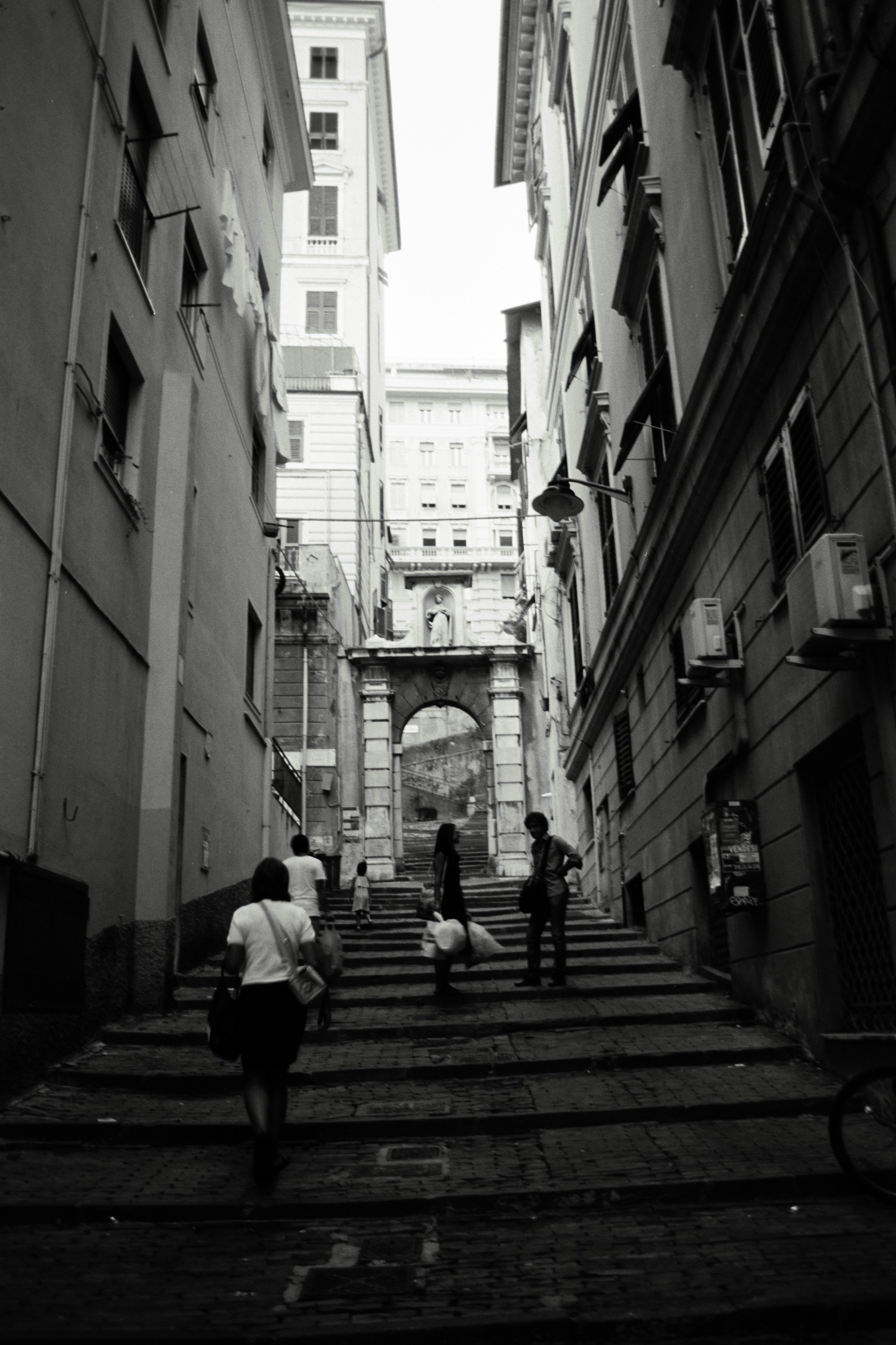 People ascend stairs on a narrow european street.