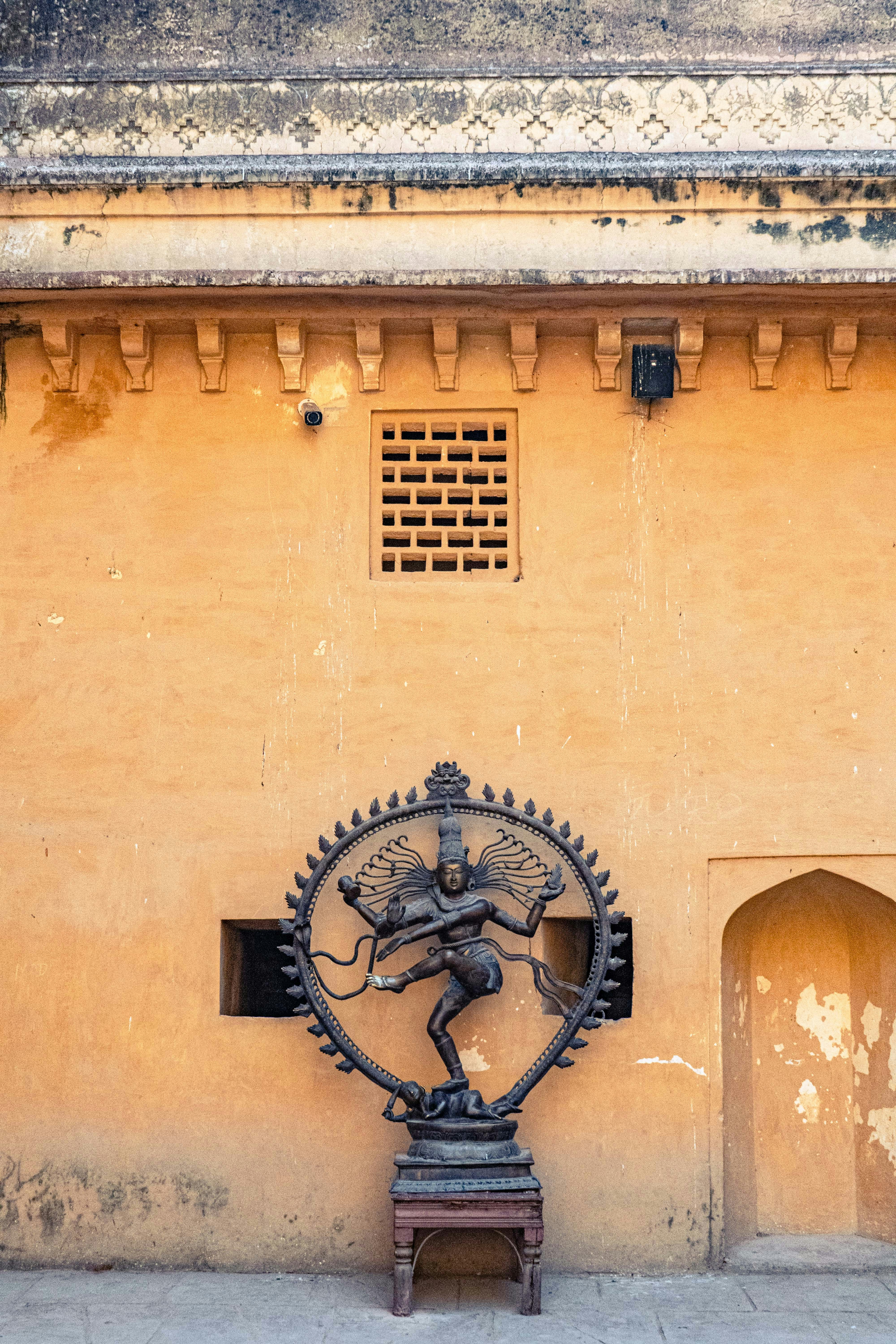 Bronzestatue des tanzenden Shiva vor einer gelben Wand