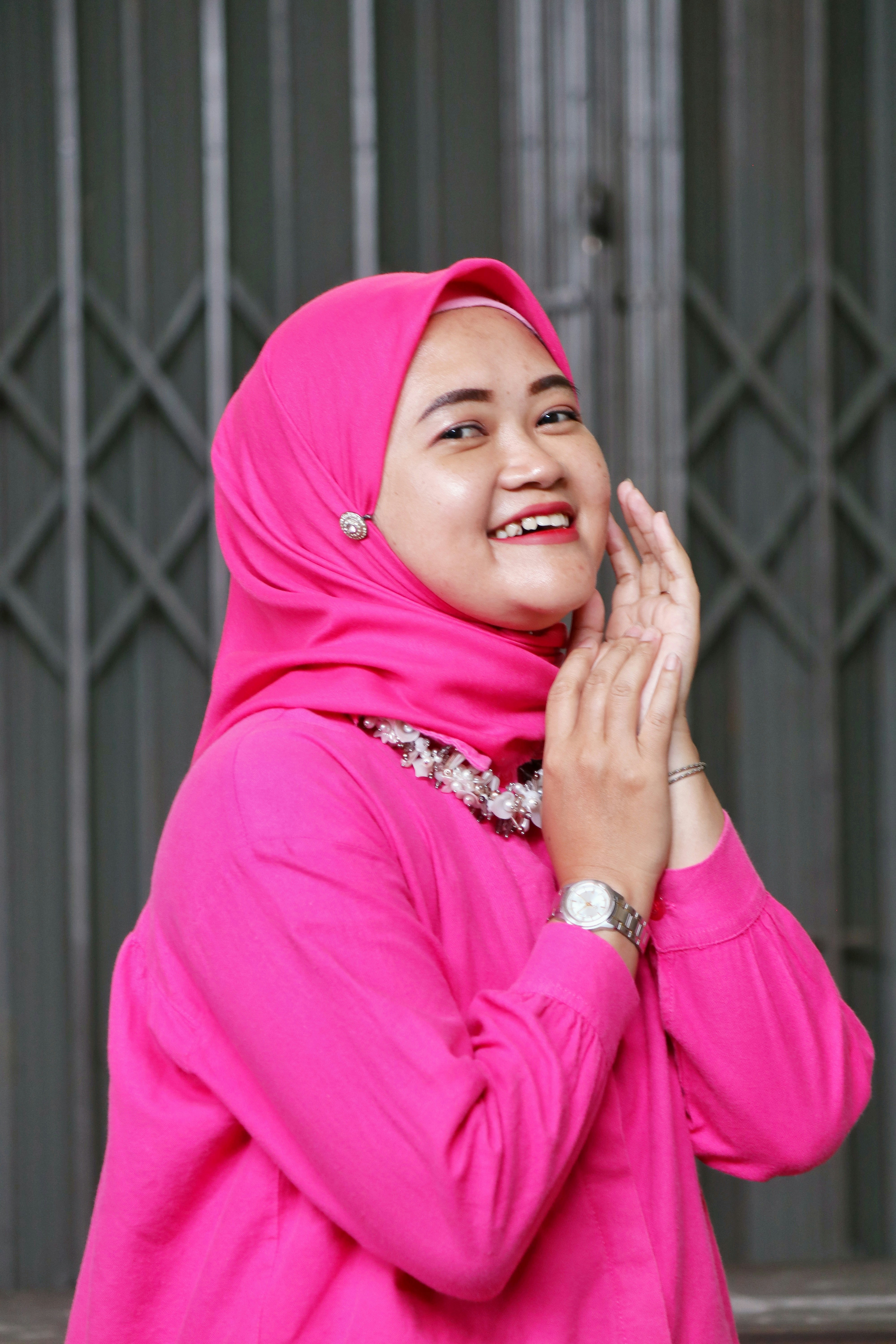 A smiling woman in a pink hijab and dress