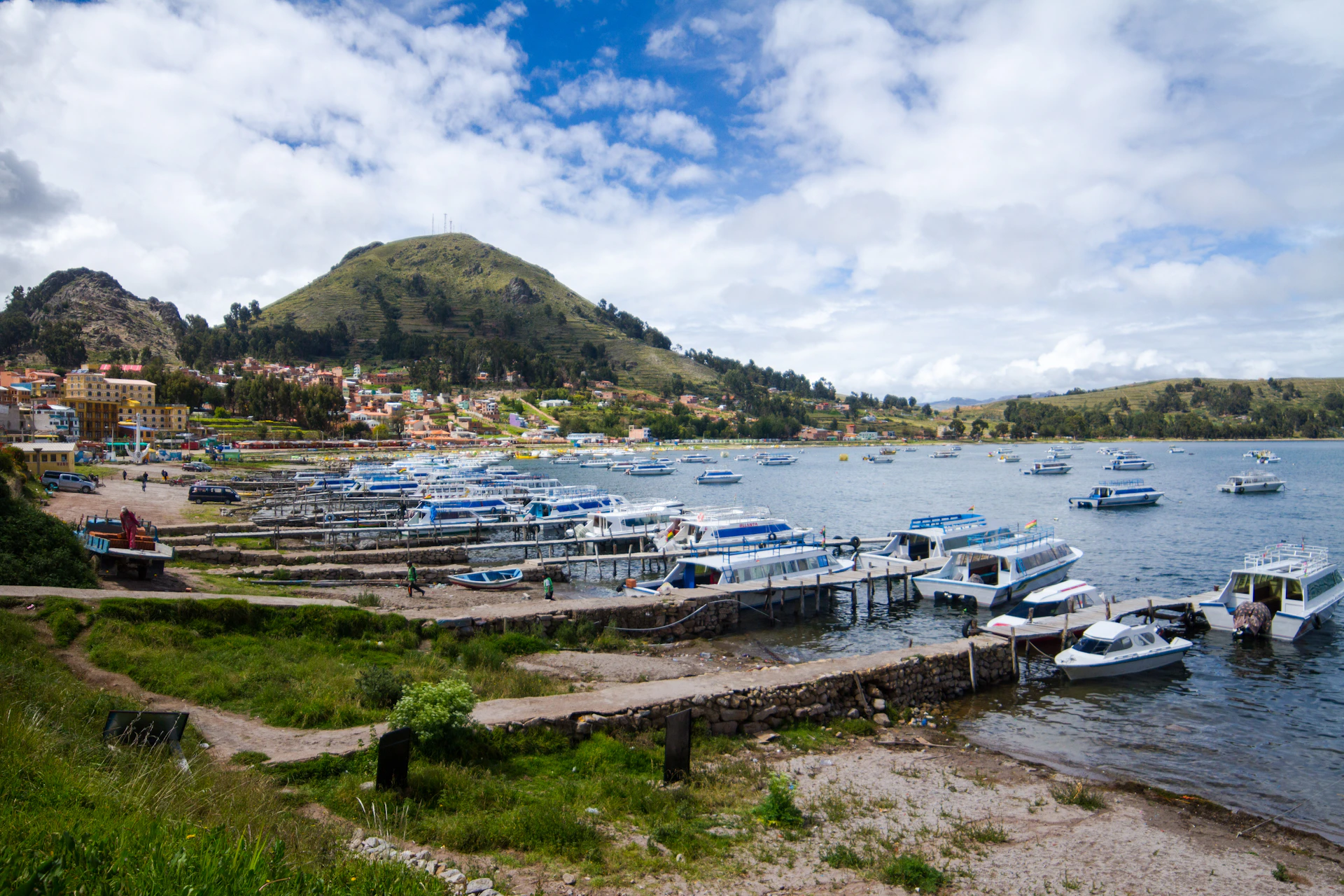 Boats docked at a lakeside town with hills.