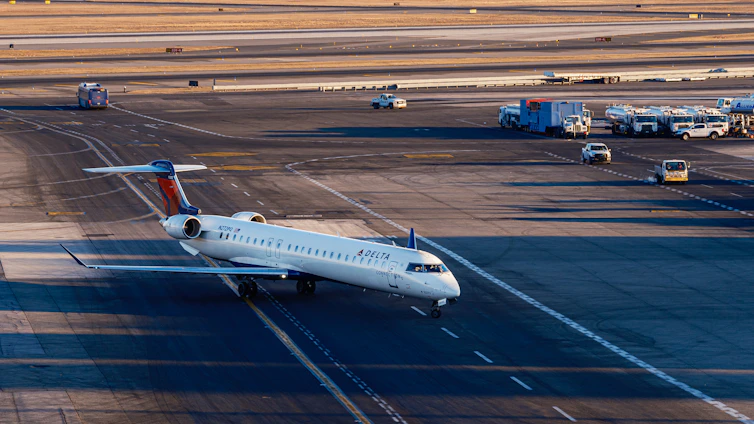 A commercial airplane taxis on an airport tarmac.