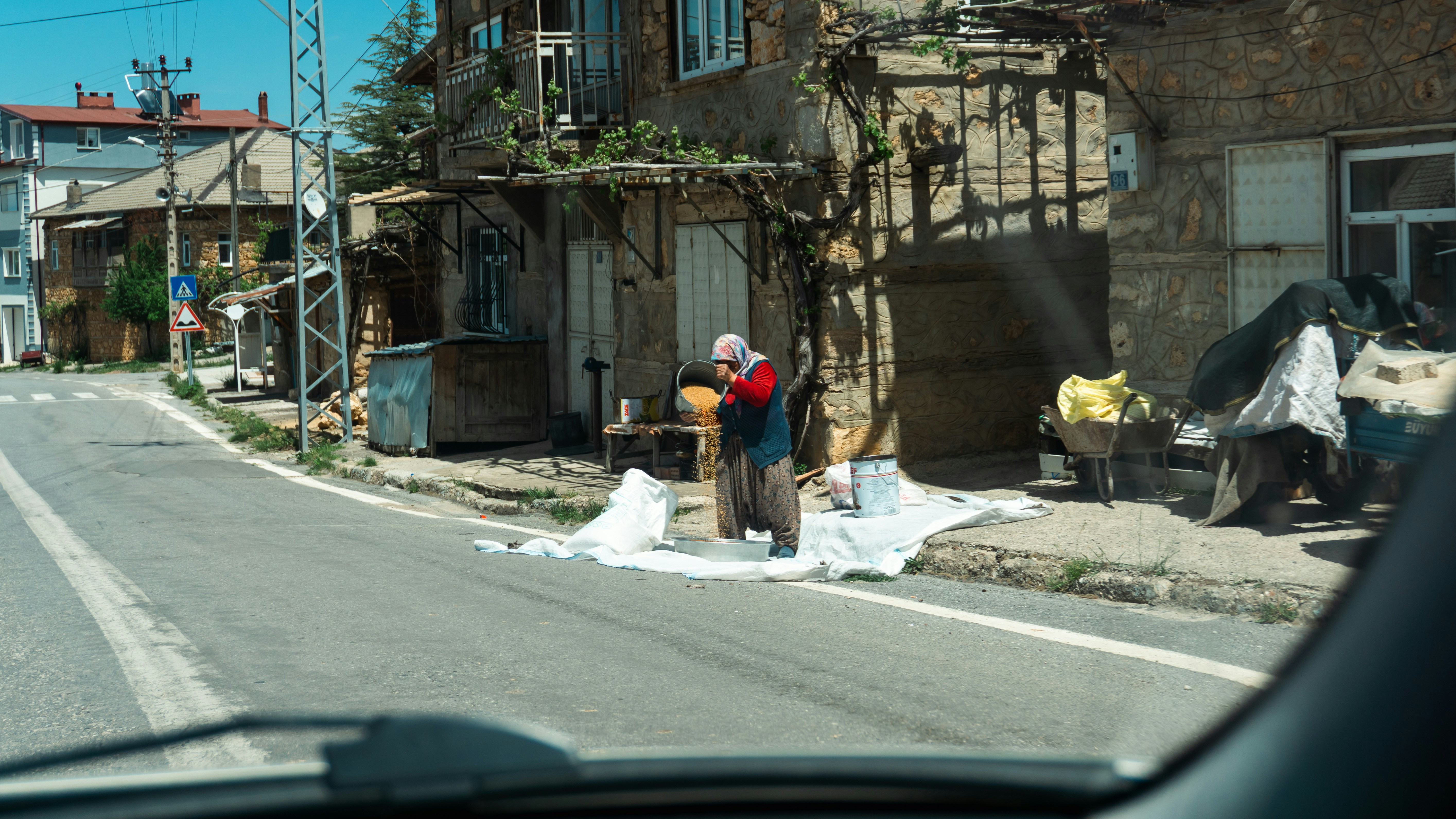 Elderly woman drying produce on a roadside