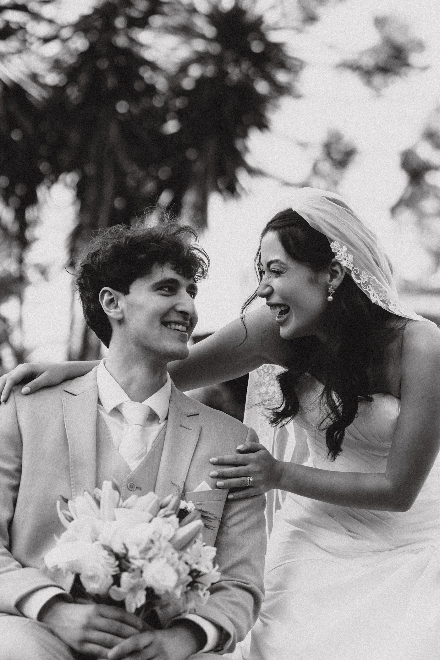 Bride and groom laughing together genuinely during wedding portrait session both in full wedding attire with unposed natural joy