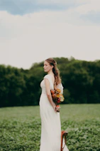 Bride holding a bouquet behind her back in a field