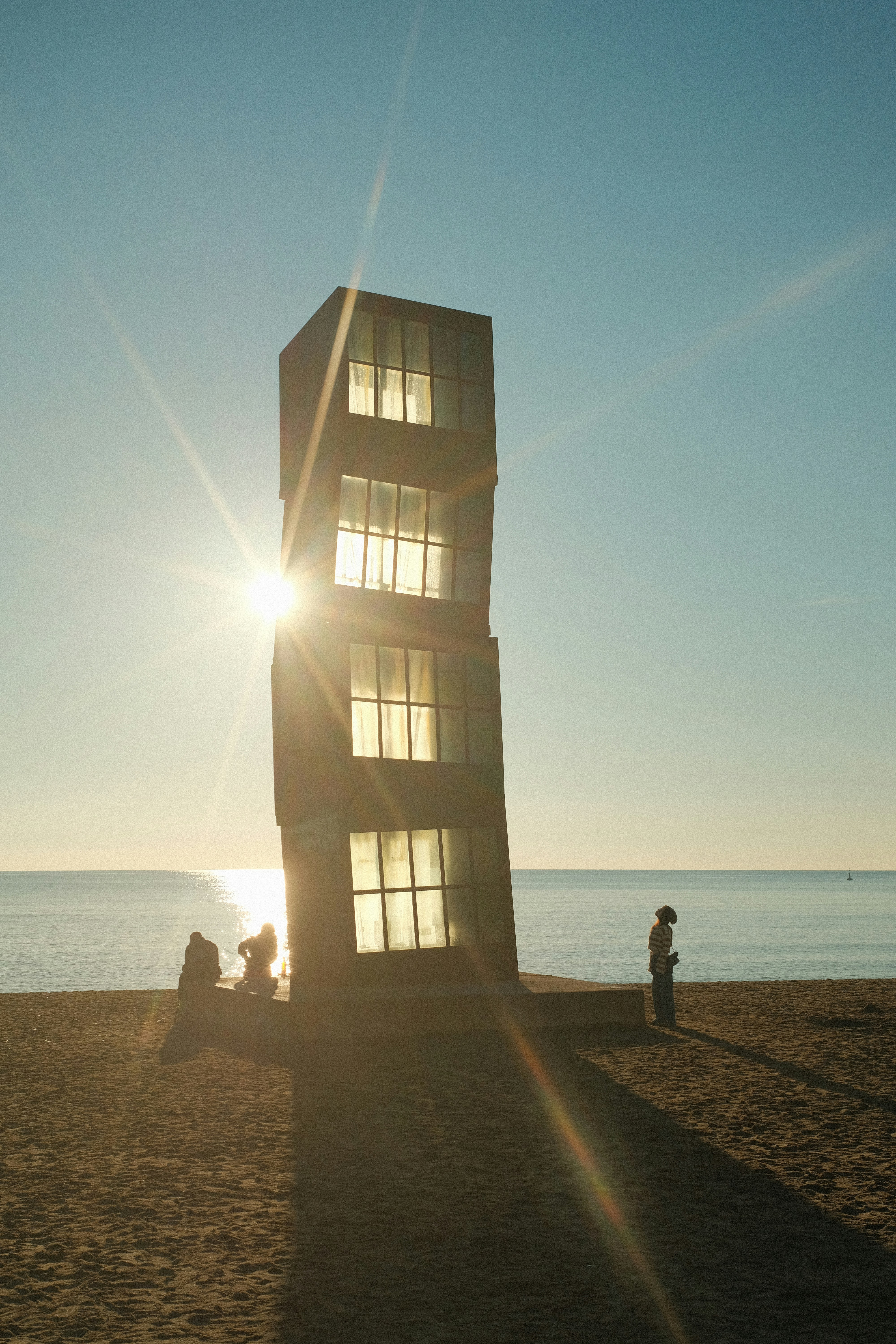 Escultura moderna en la playa al atardecer con un destellos solares.