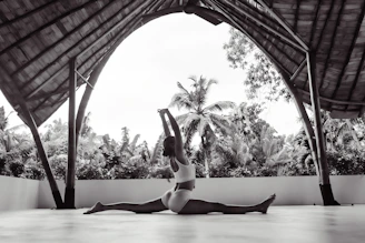 Woman in split pose under open-air pavilion.