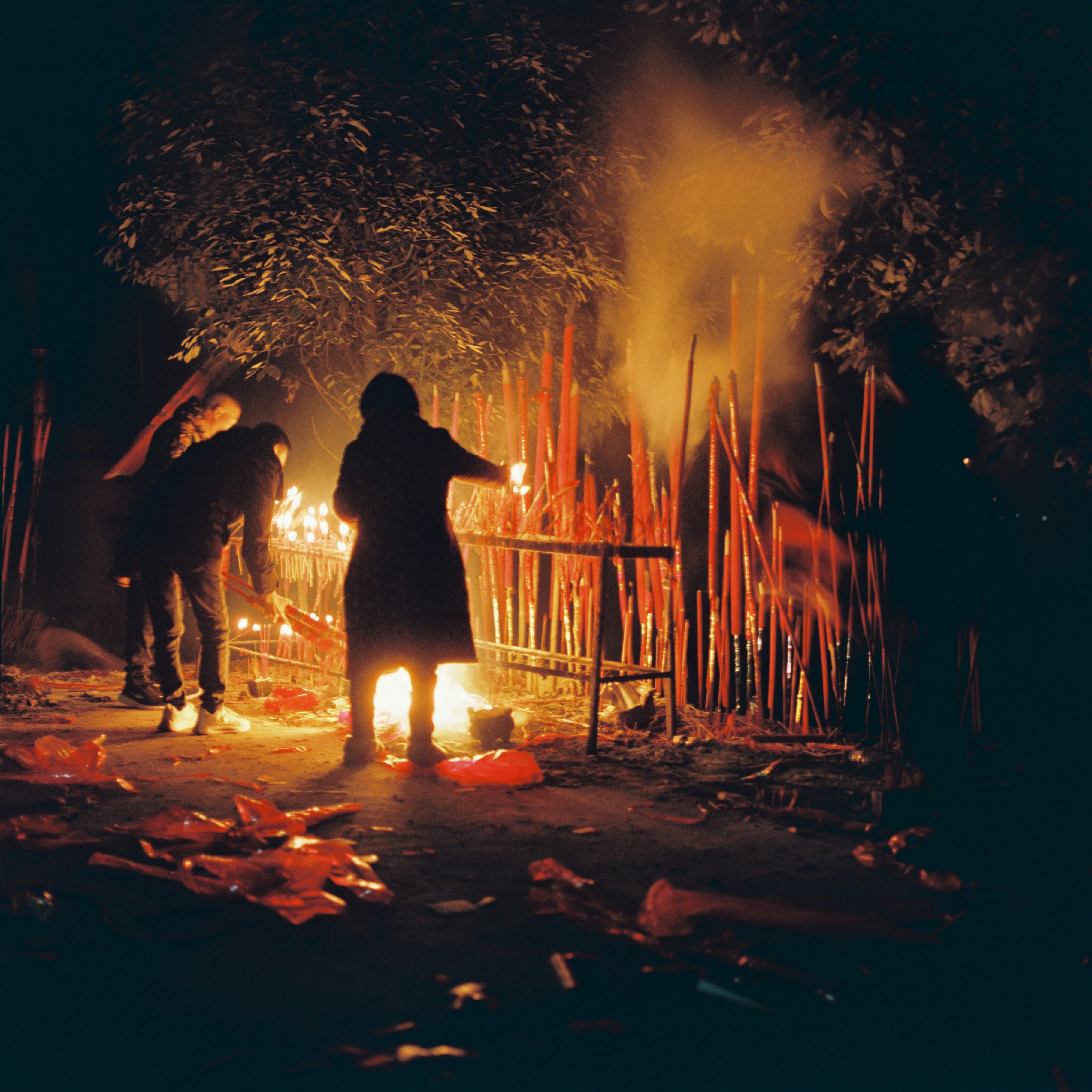 People lighting incense sticks at night with smoke
