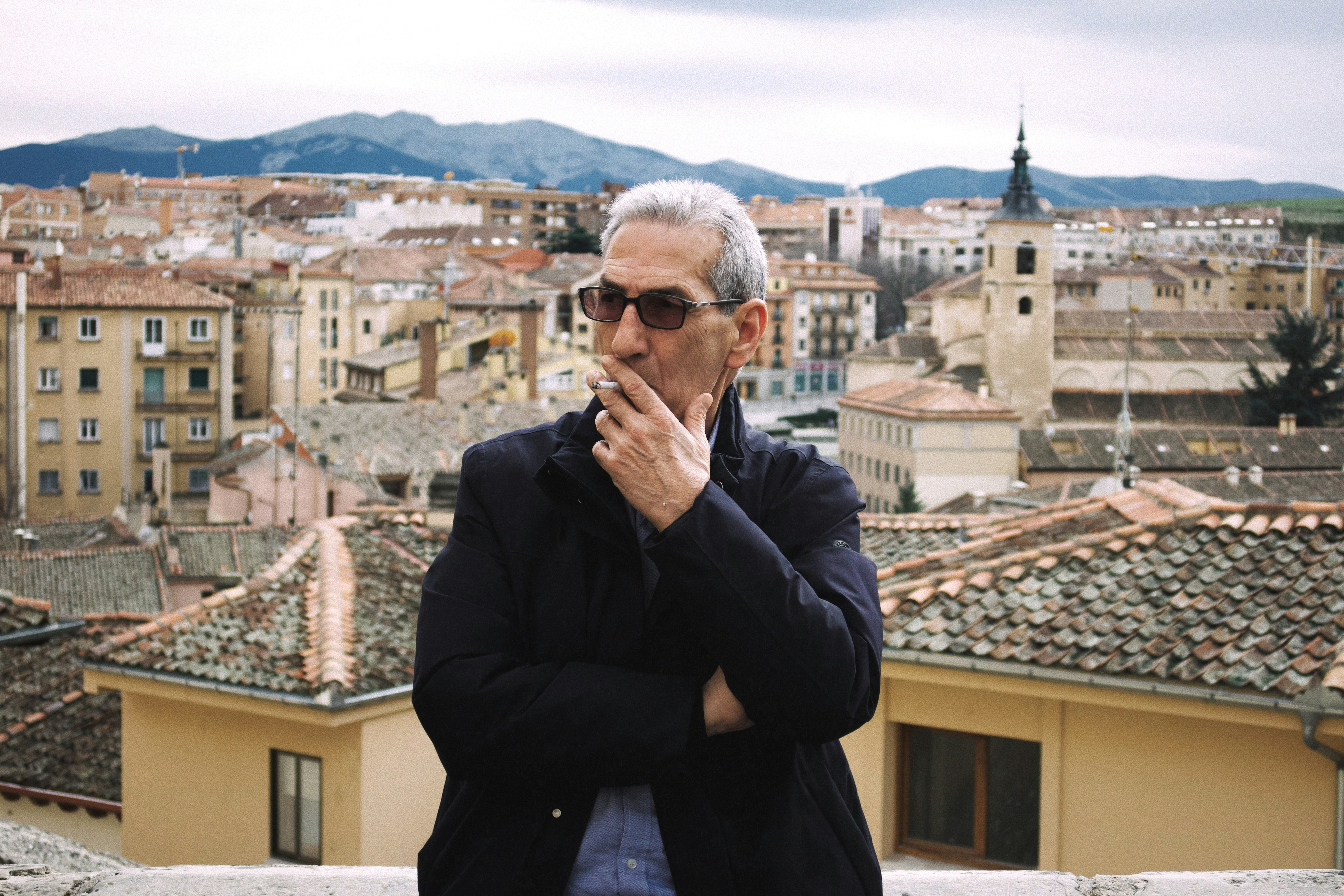Homme fumant une cigarette avec la ville en fond sonore