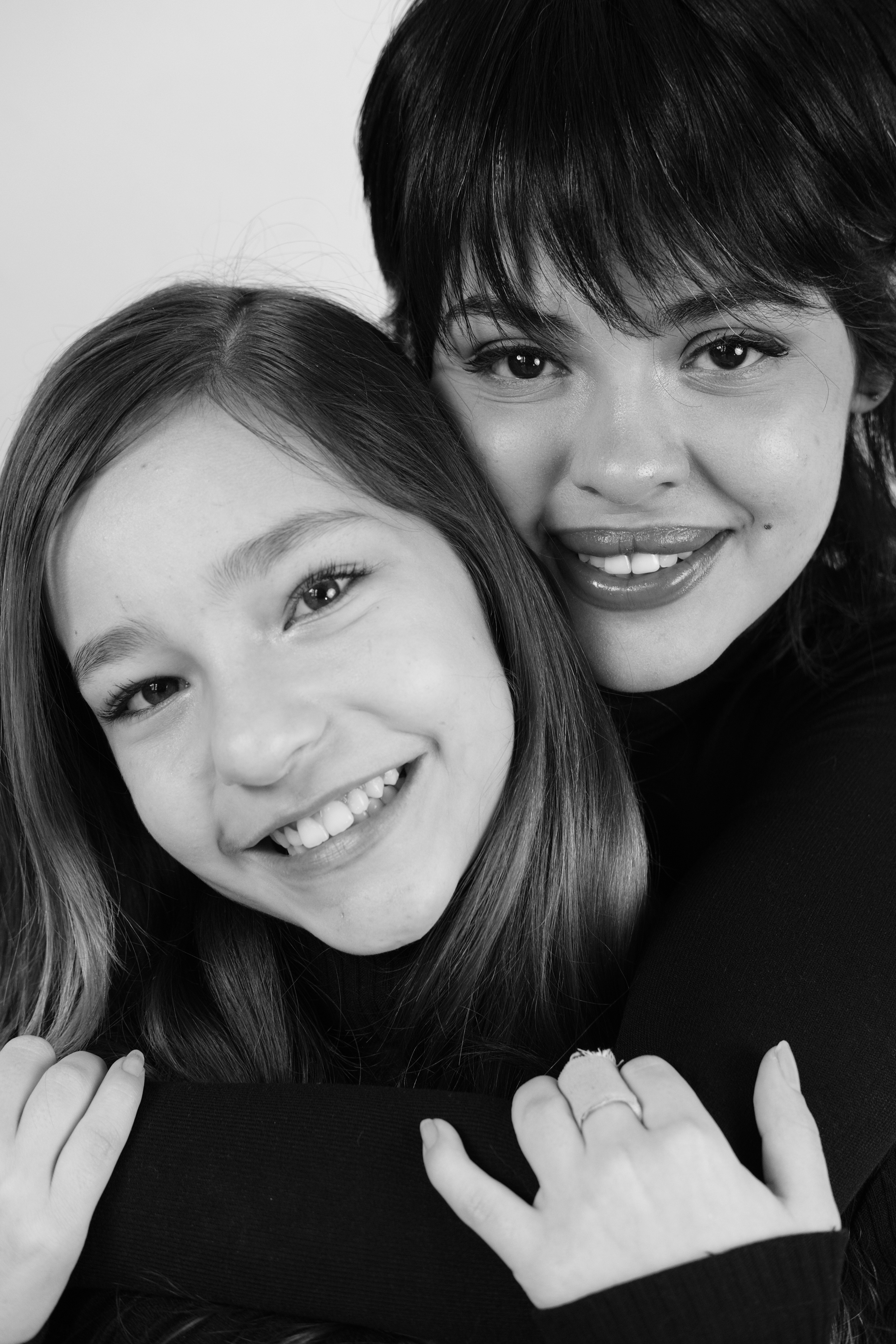 Deux femmes souriantes s’enlaçant en noir et blanc.