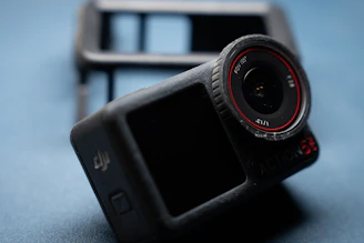 A black action camera with a red lens ring.