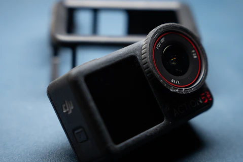 A black action camera with a red lens ring.