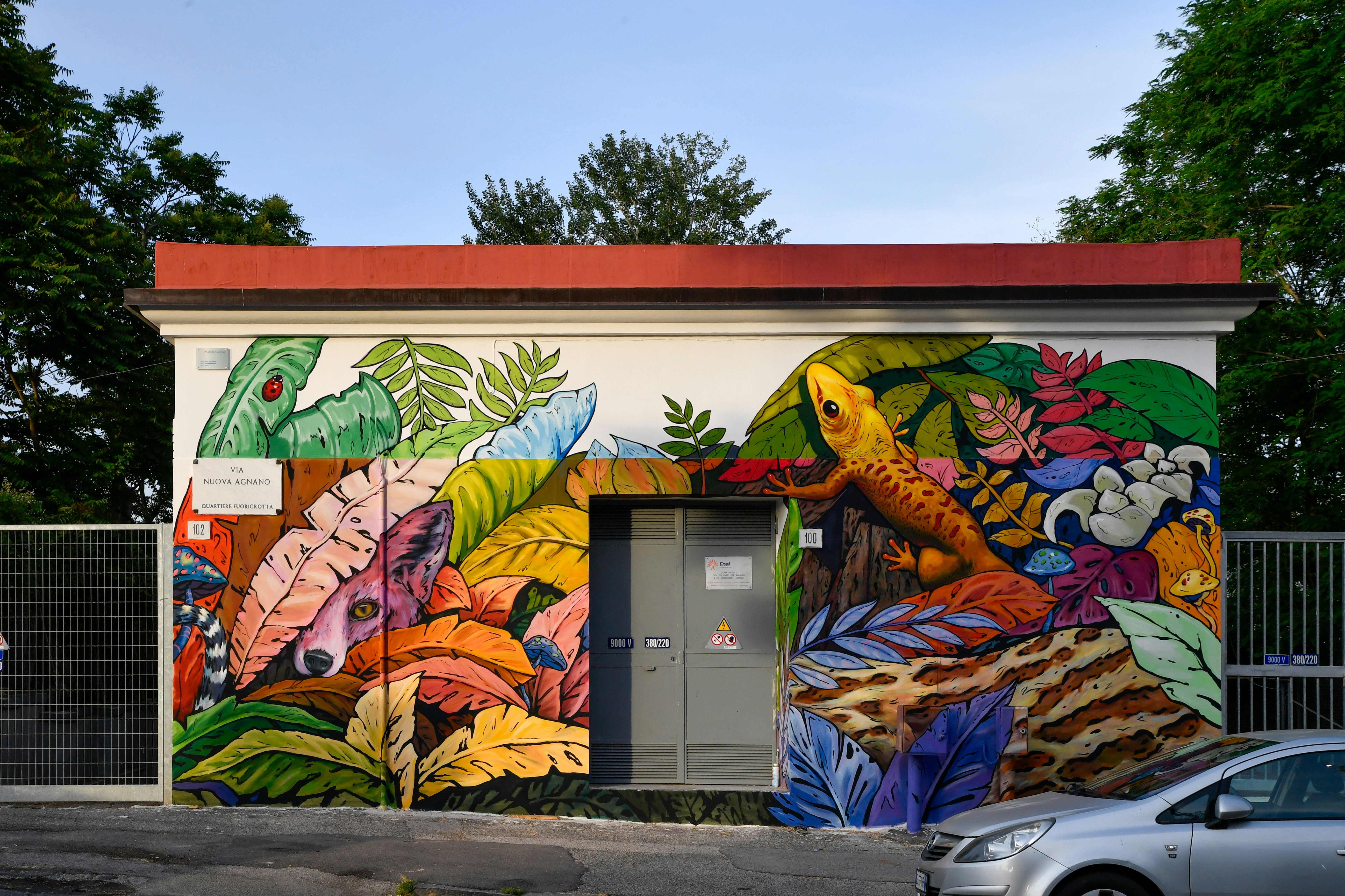 A building mural with a lizard and tropical plants.