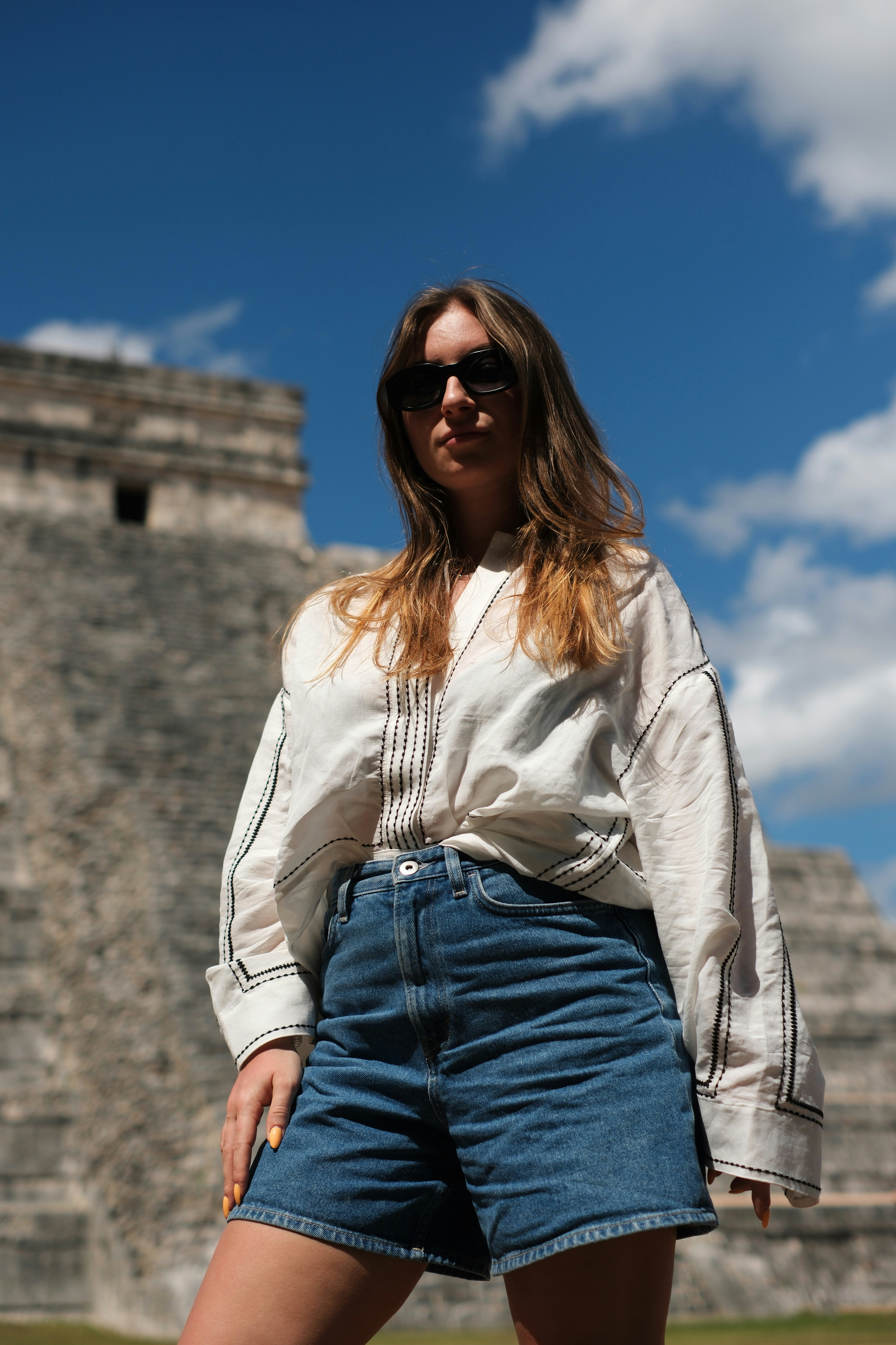 Mujer con gafas de sol de pie ante la antigua pirámide