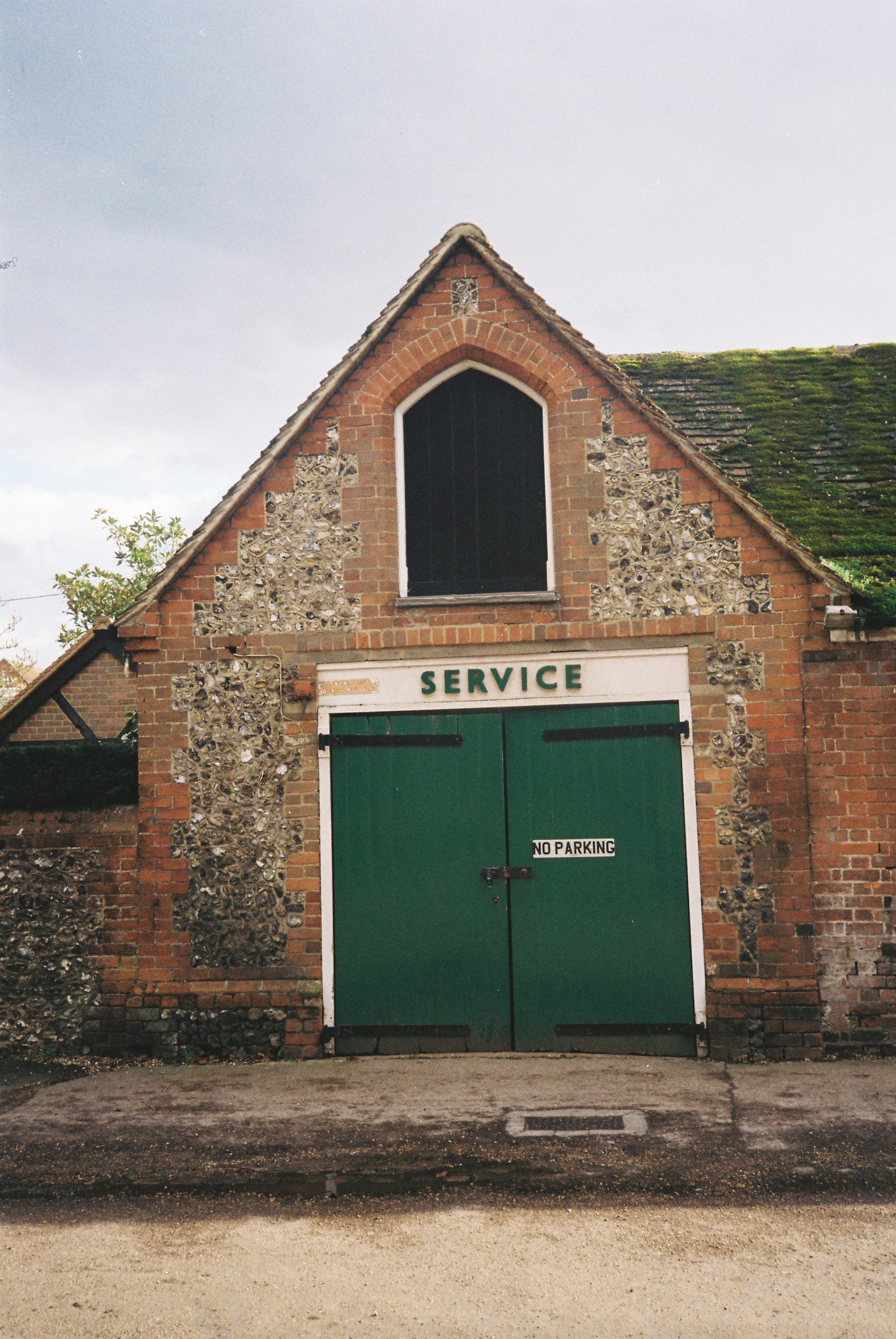 Brick building with green double doors and "service" sign