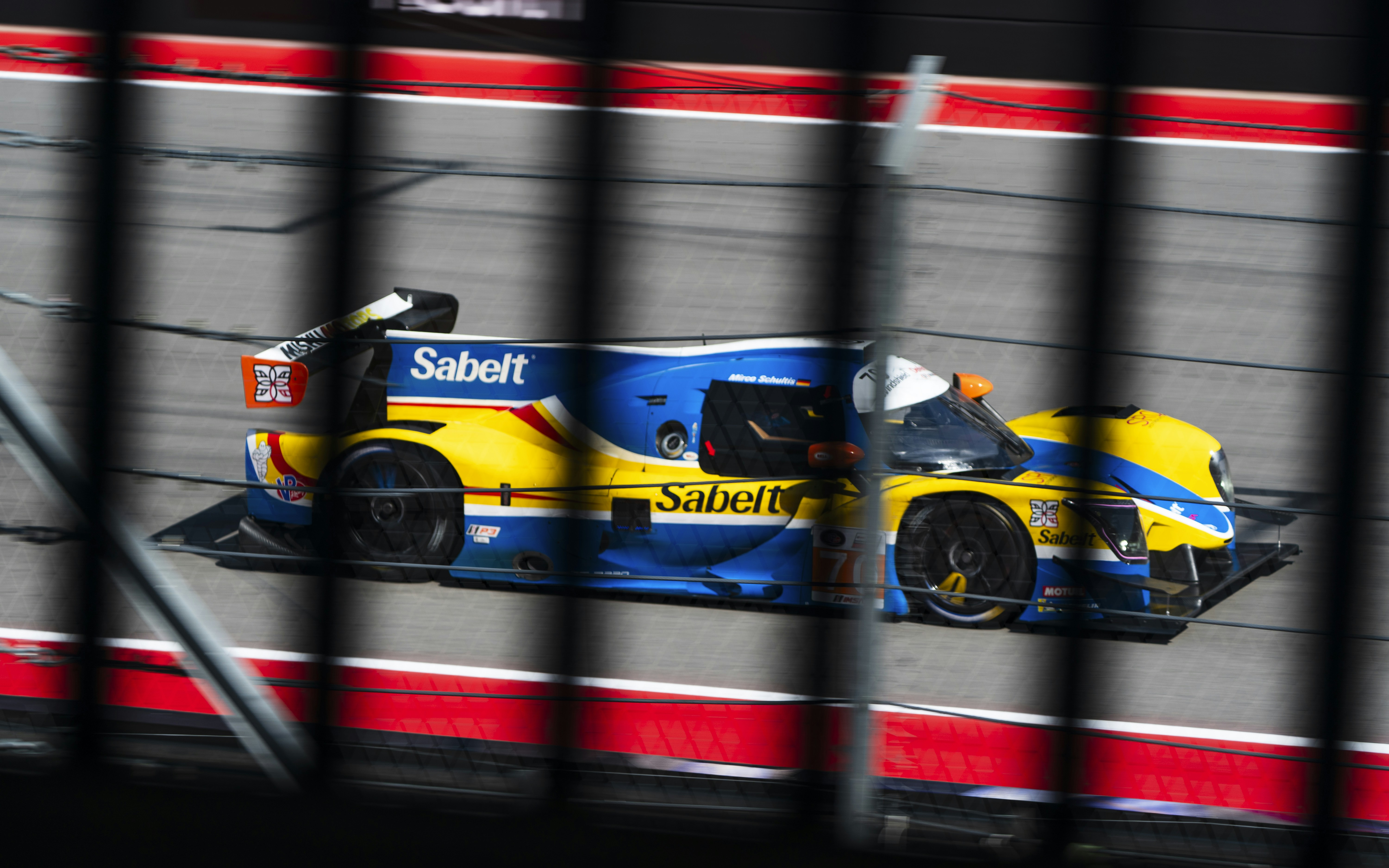 A blue and yellow race car speeds on a track.