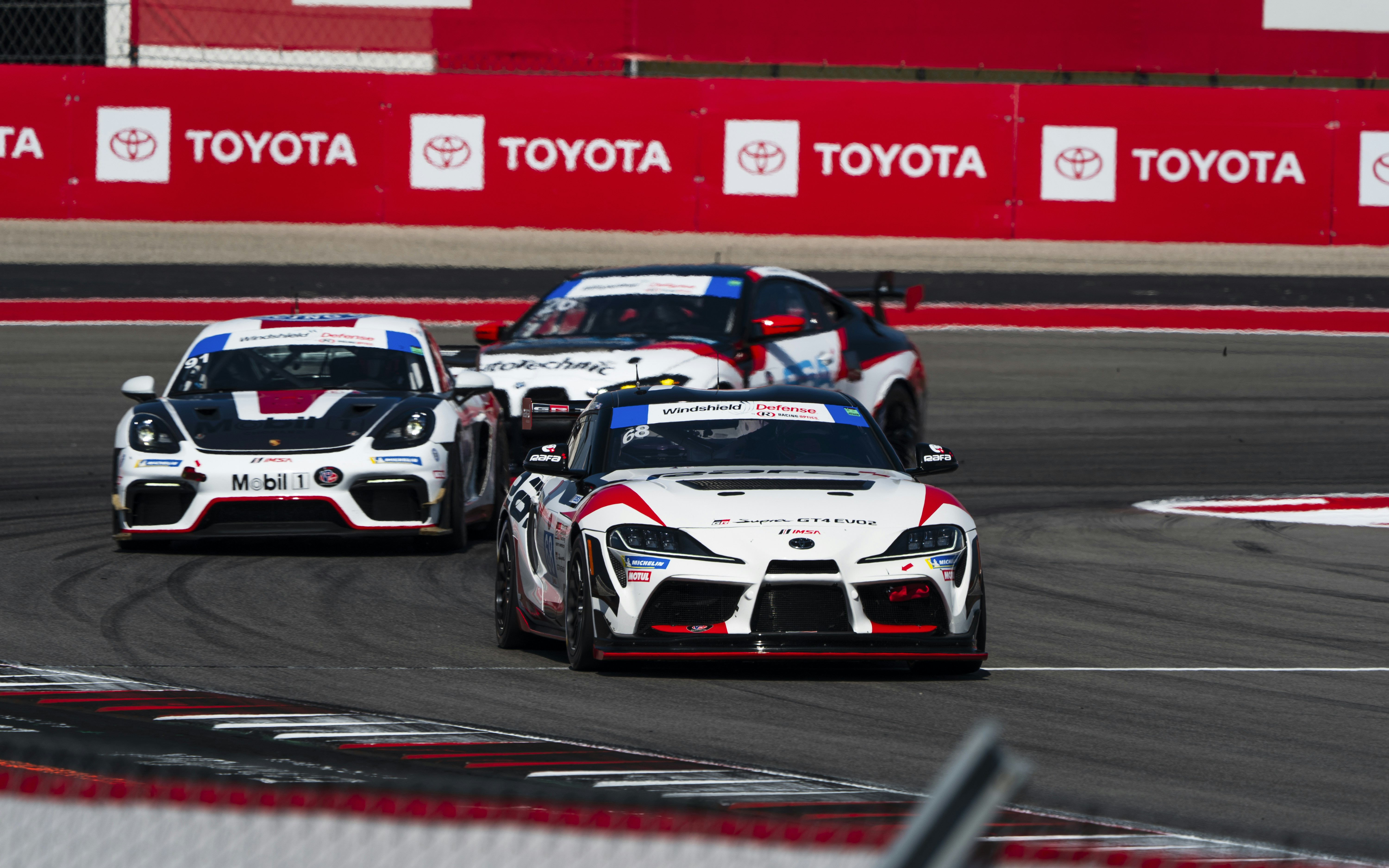 Three race cars speed around a track