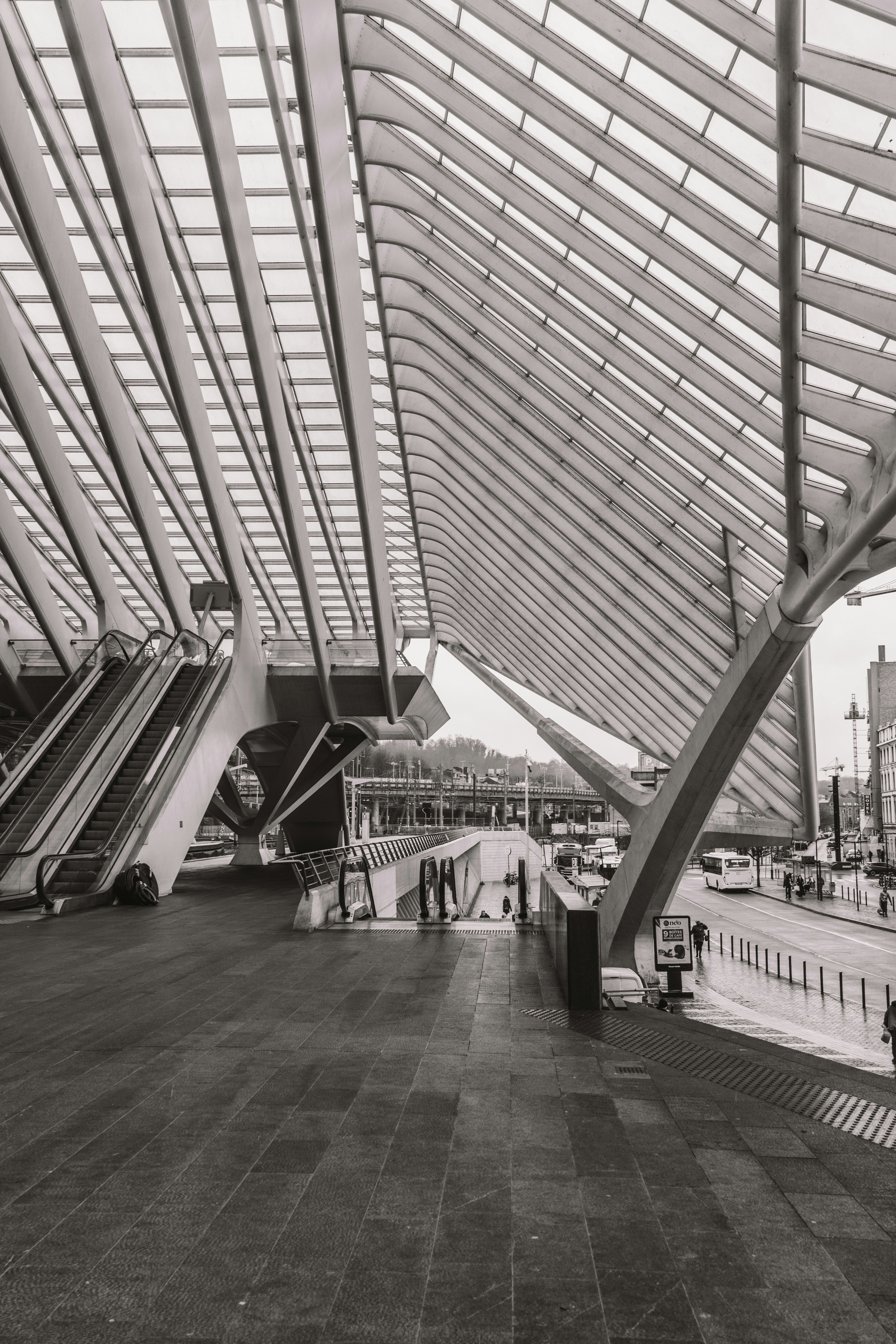 Modern train station architecture with escalators and glass roof.