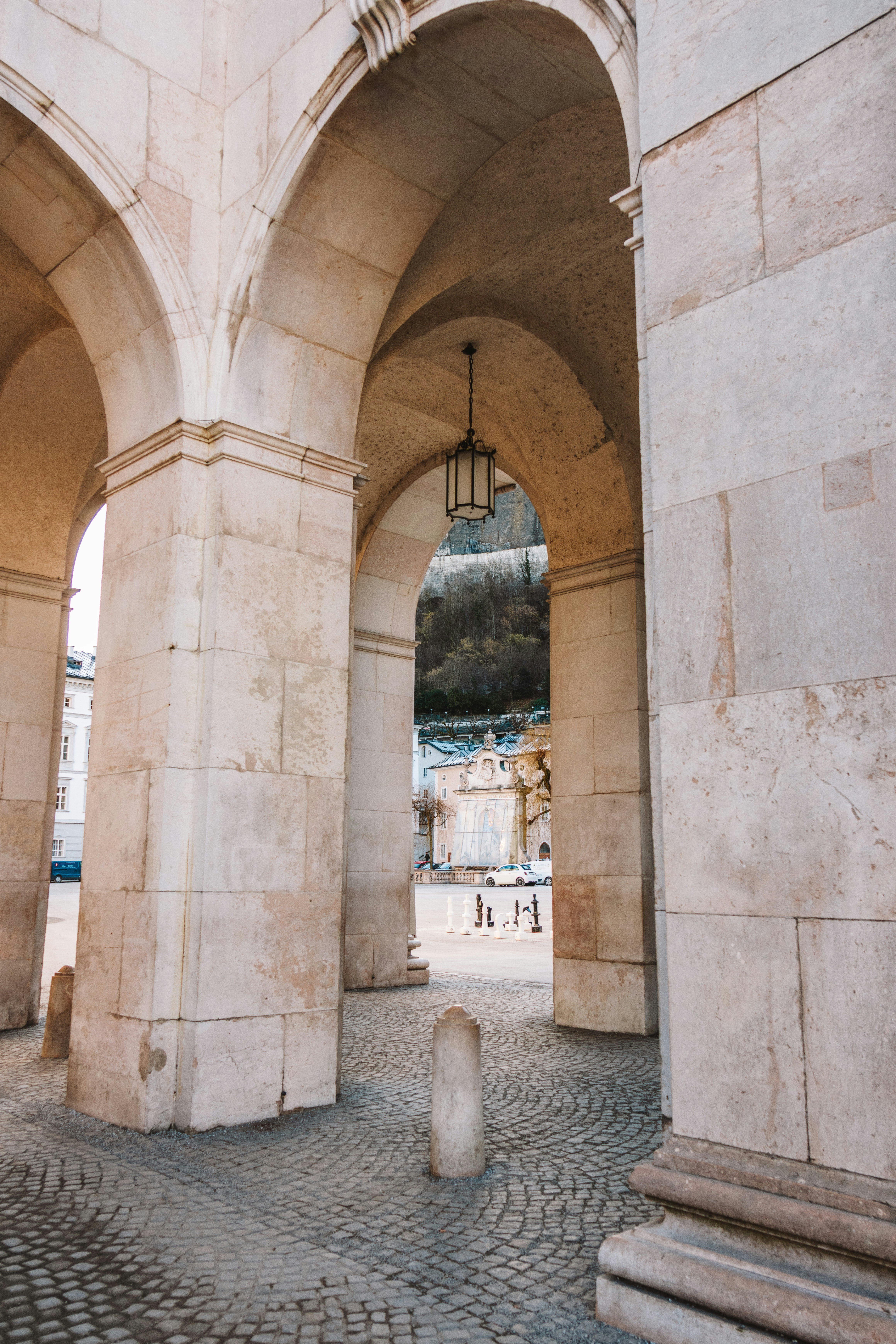 Stone arches and cobblestone path leading to a plaza.
