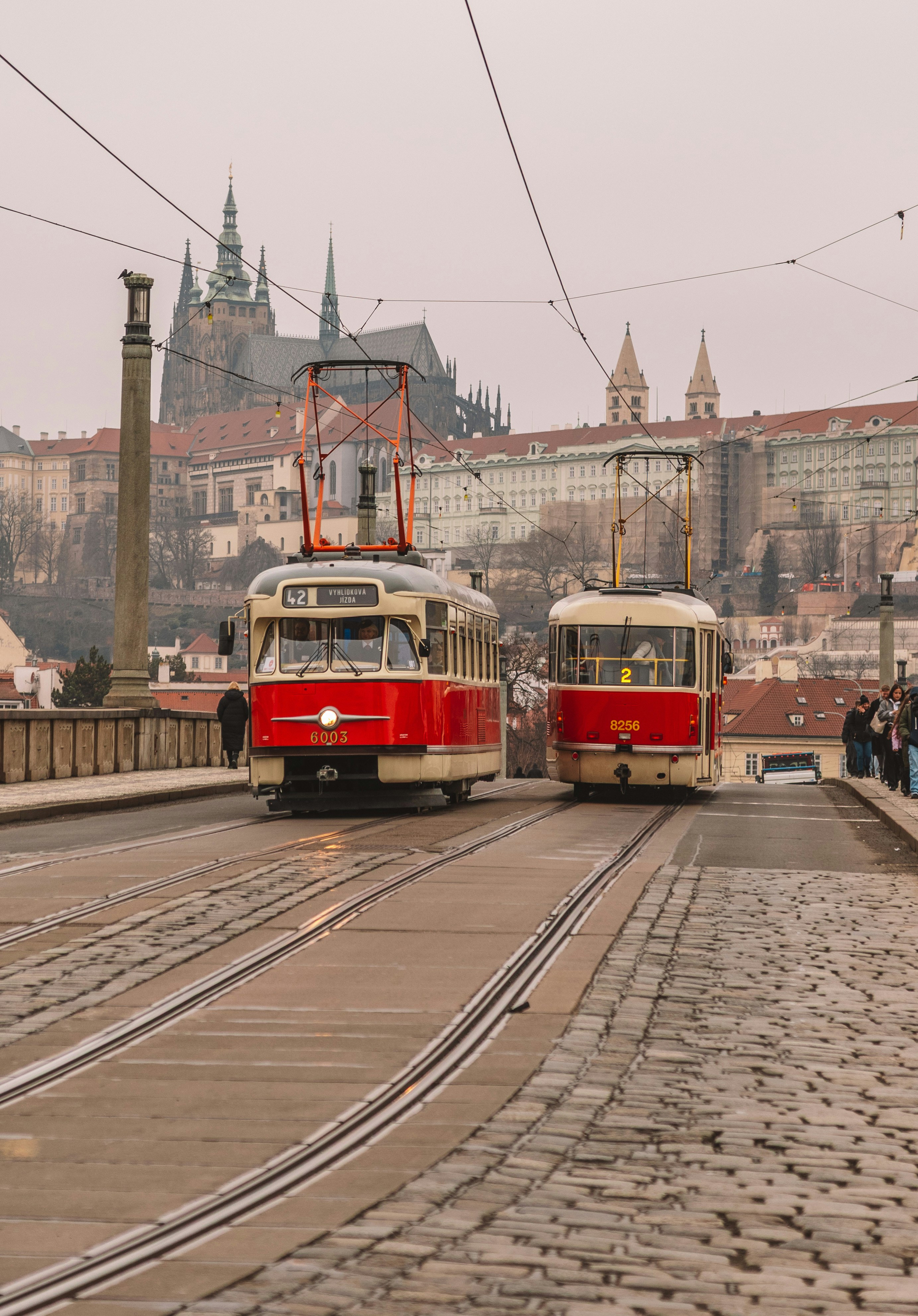 Two vintage trams on a cobblestone bridge in prague