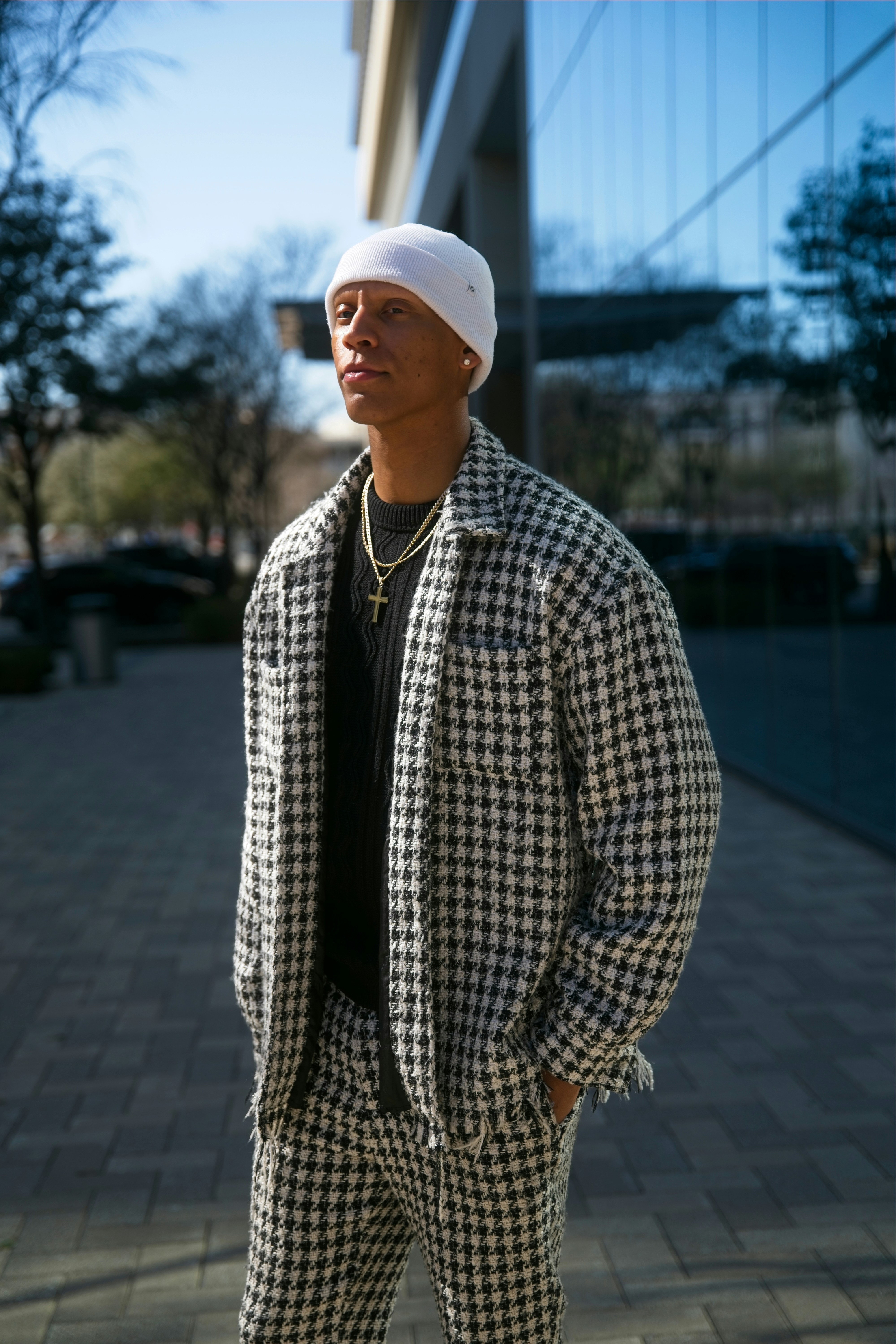 Homem com terno de pente-de-galo e gorro do lado de fora do prédio