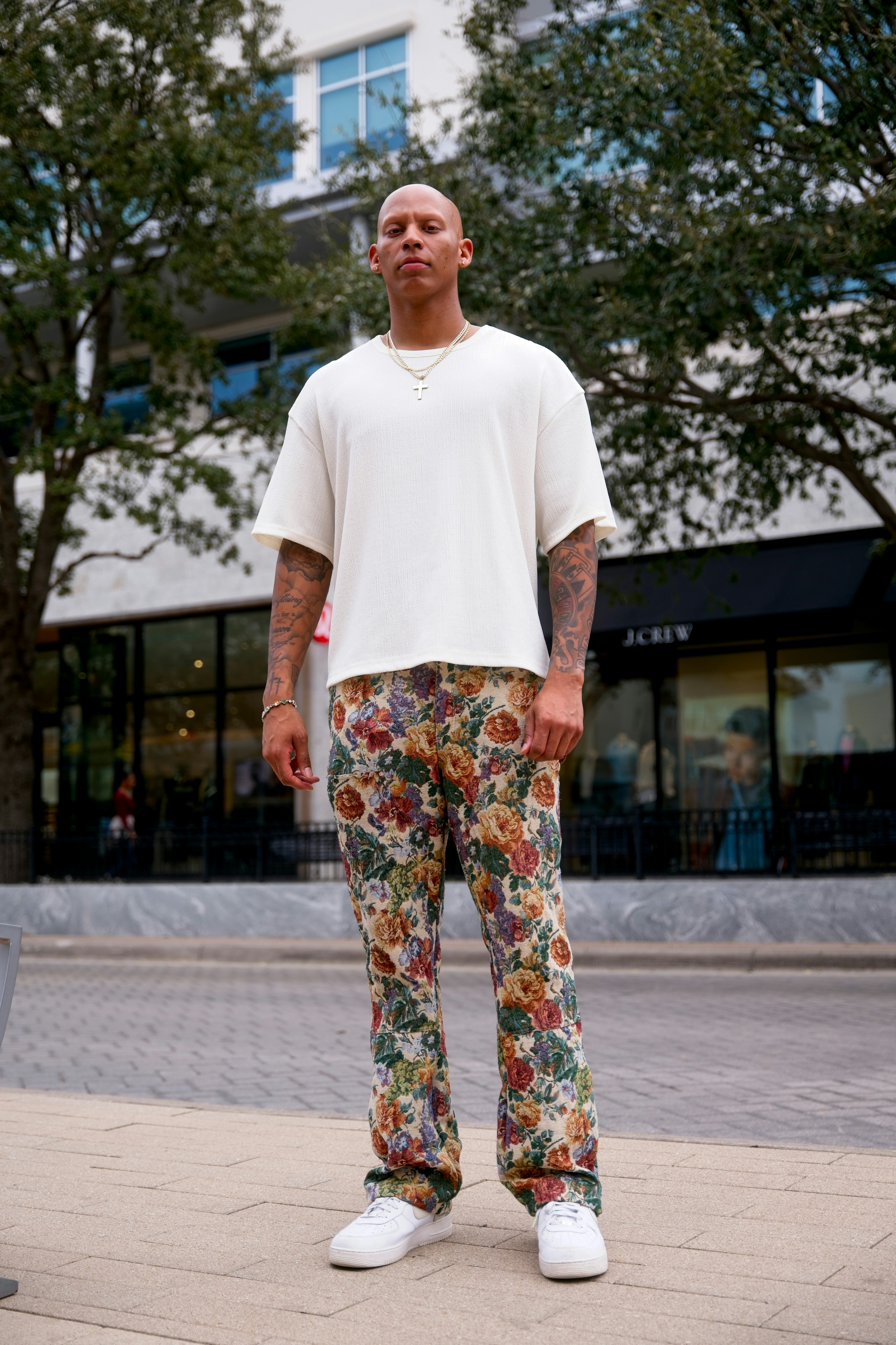 Homem usando camiseta branca e calça floral.