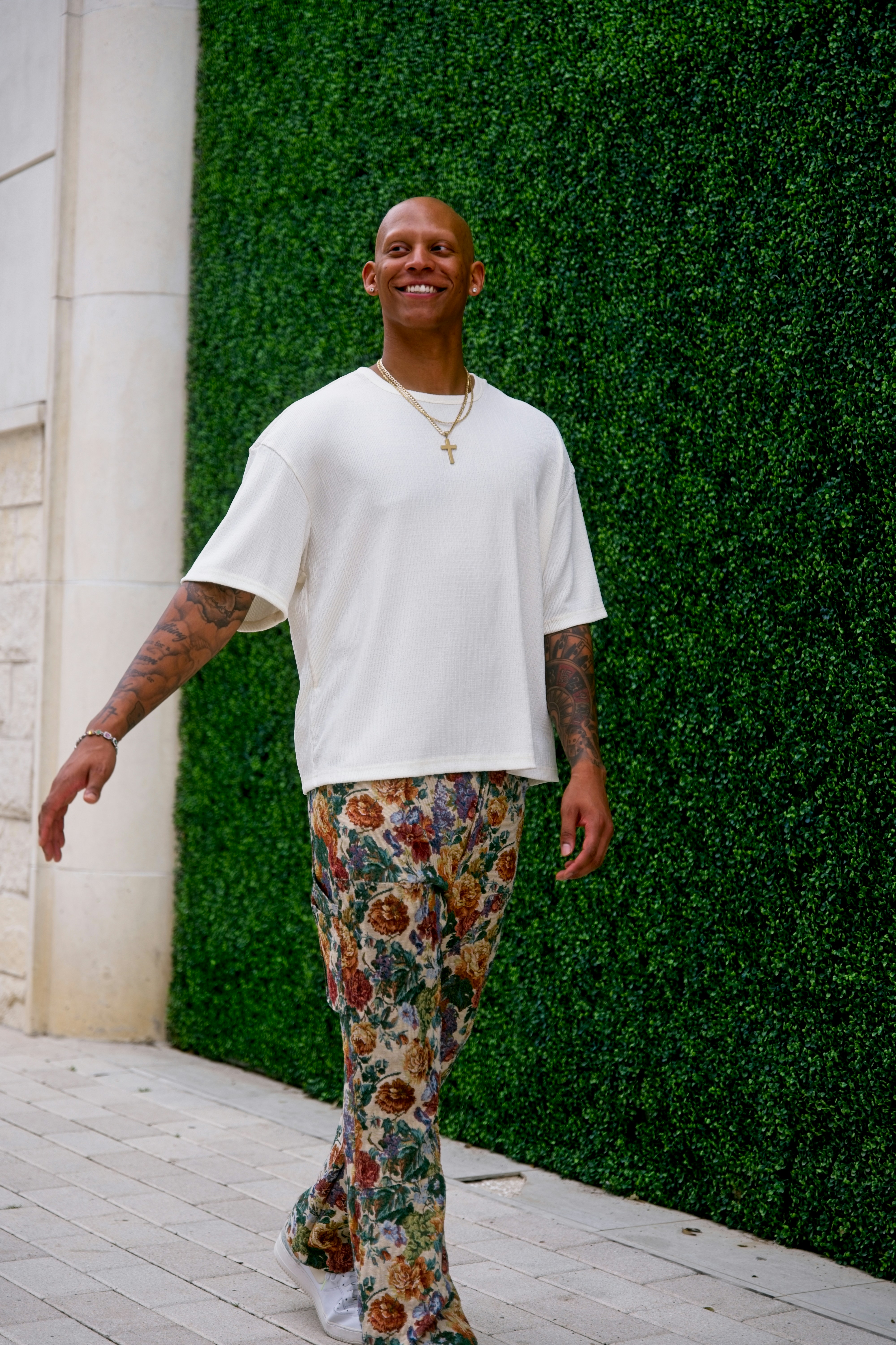 Homem de calça estampada e camisa branca sai para fora.