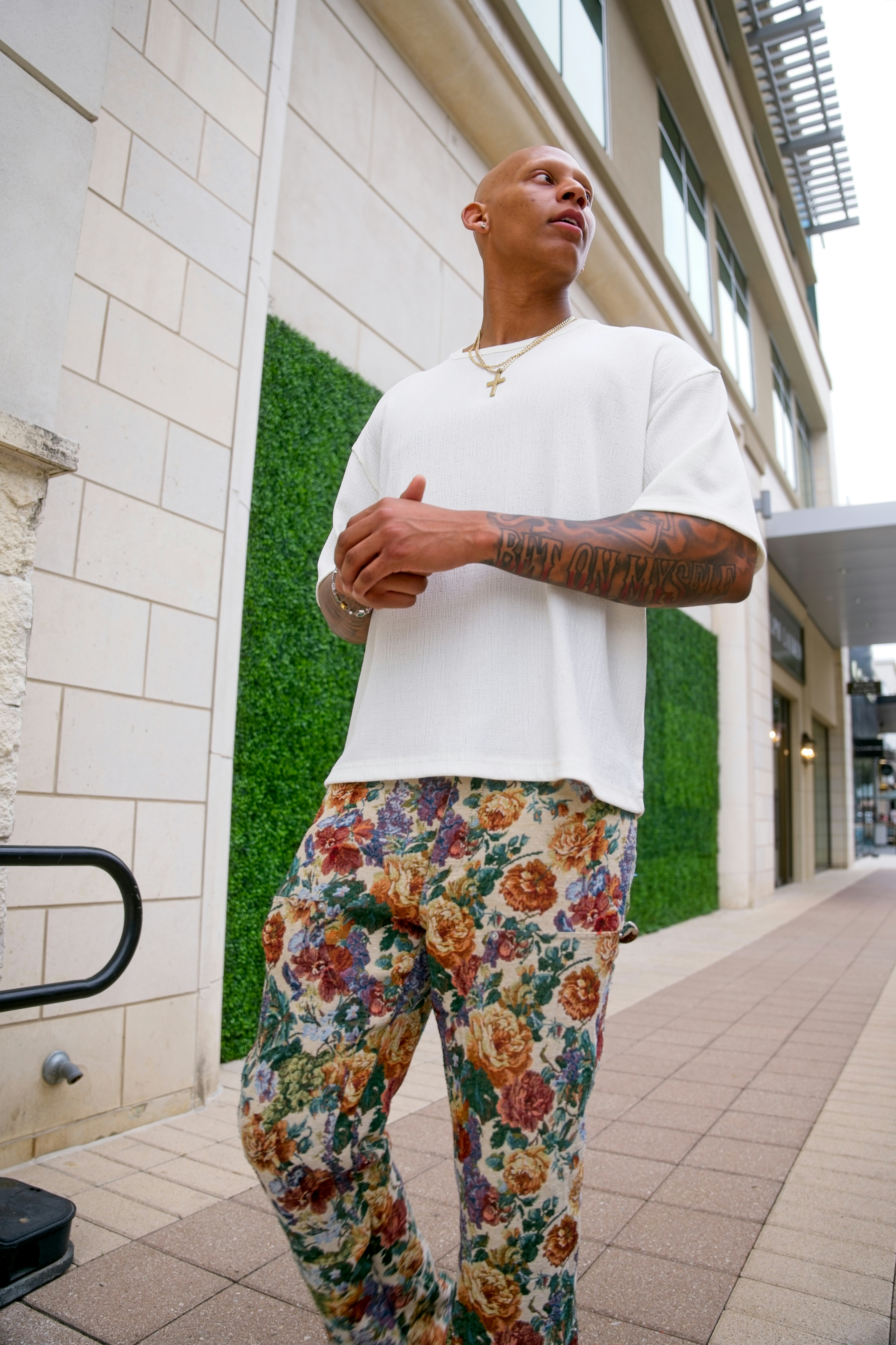Homem de calça floral e camisa branca ao ar livre