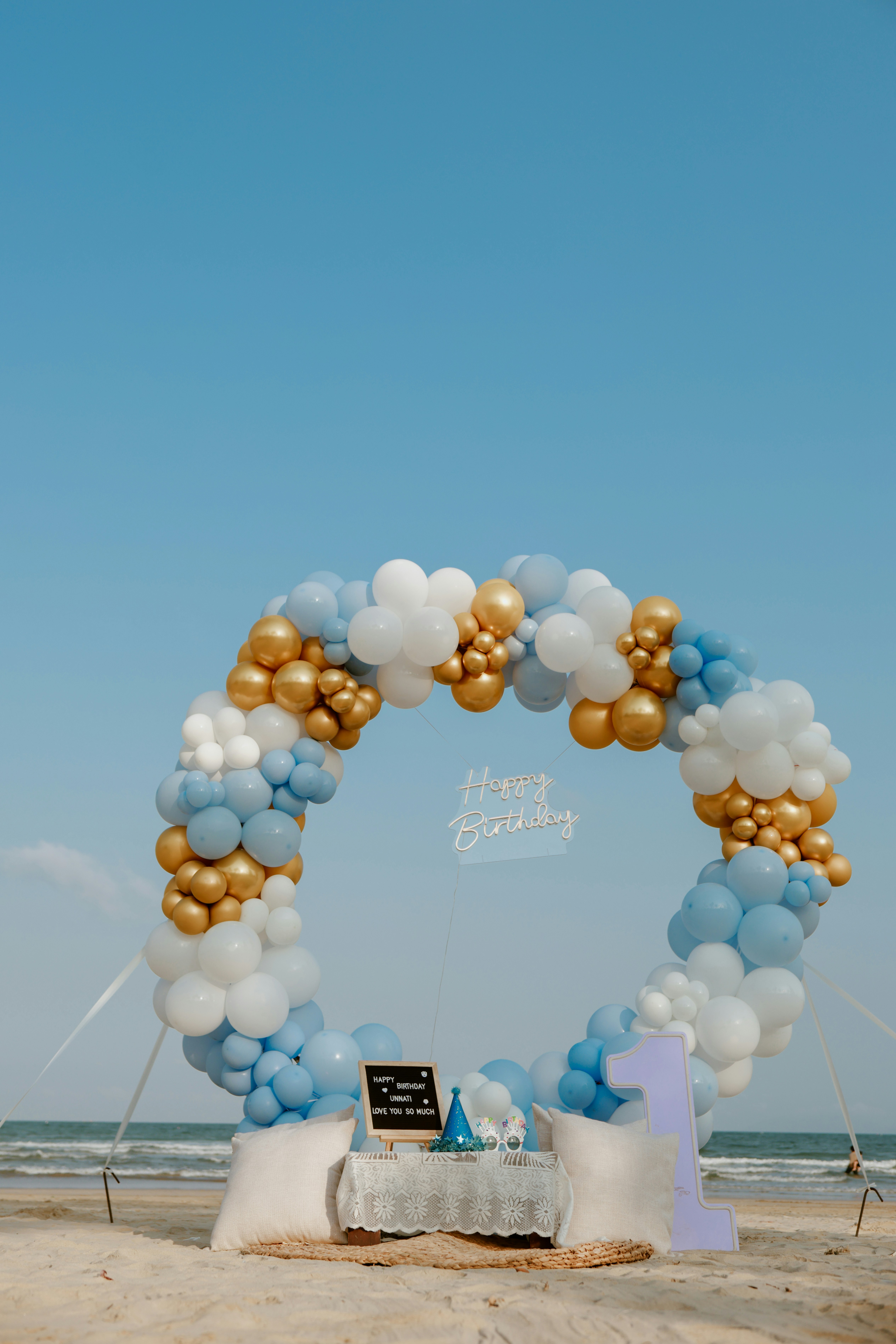 Beach birthday setup with balloons and a large number one