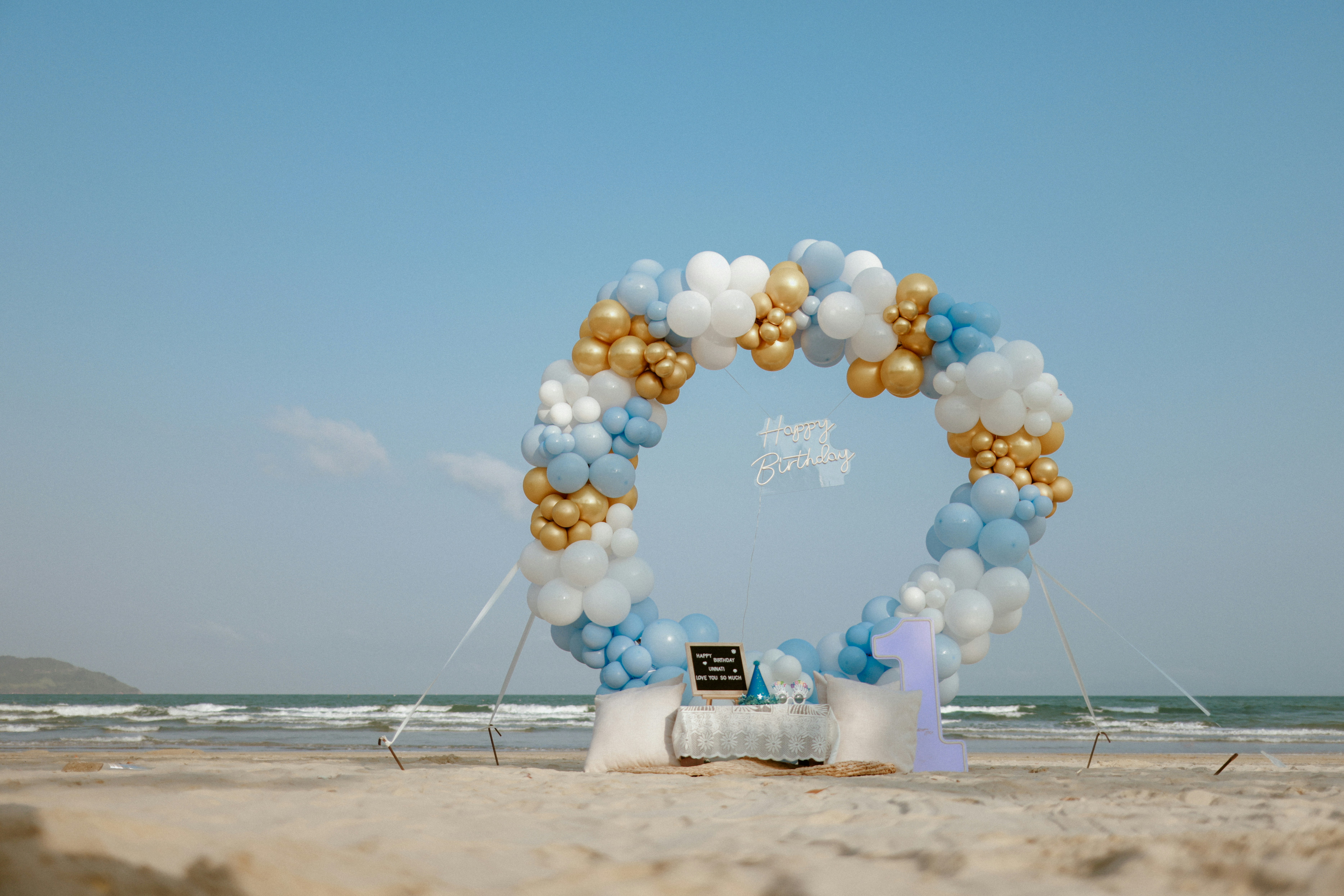 Circular balloon arch on a beach with ocean background