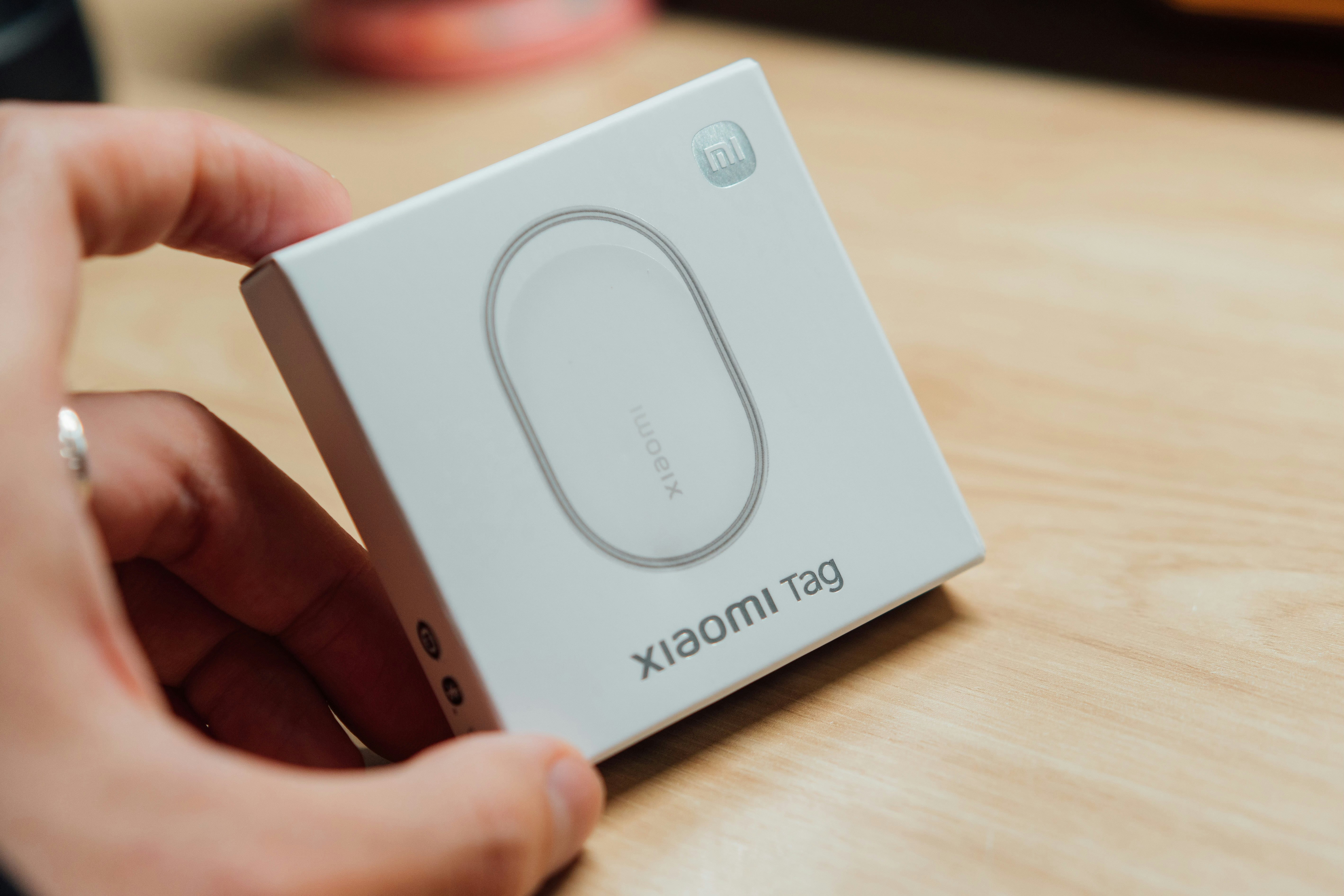 Hand holding a white box with "xiaomi tag" printed