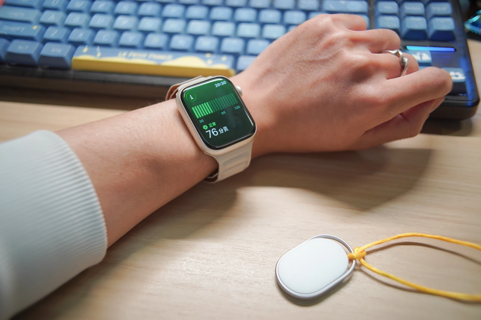 Person wearing a smartwatch with a keyboard in the background