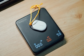 A digital scale with a small white device on top.