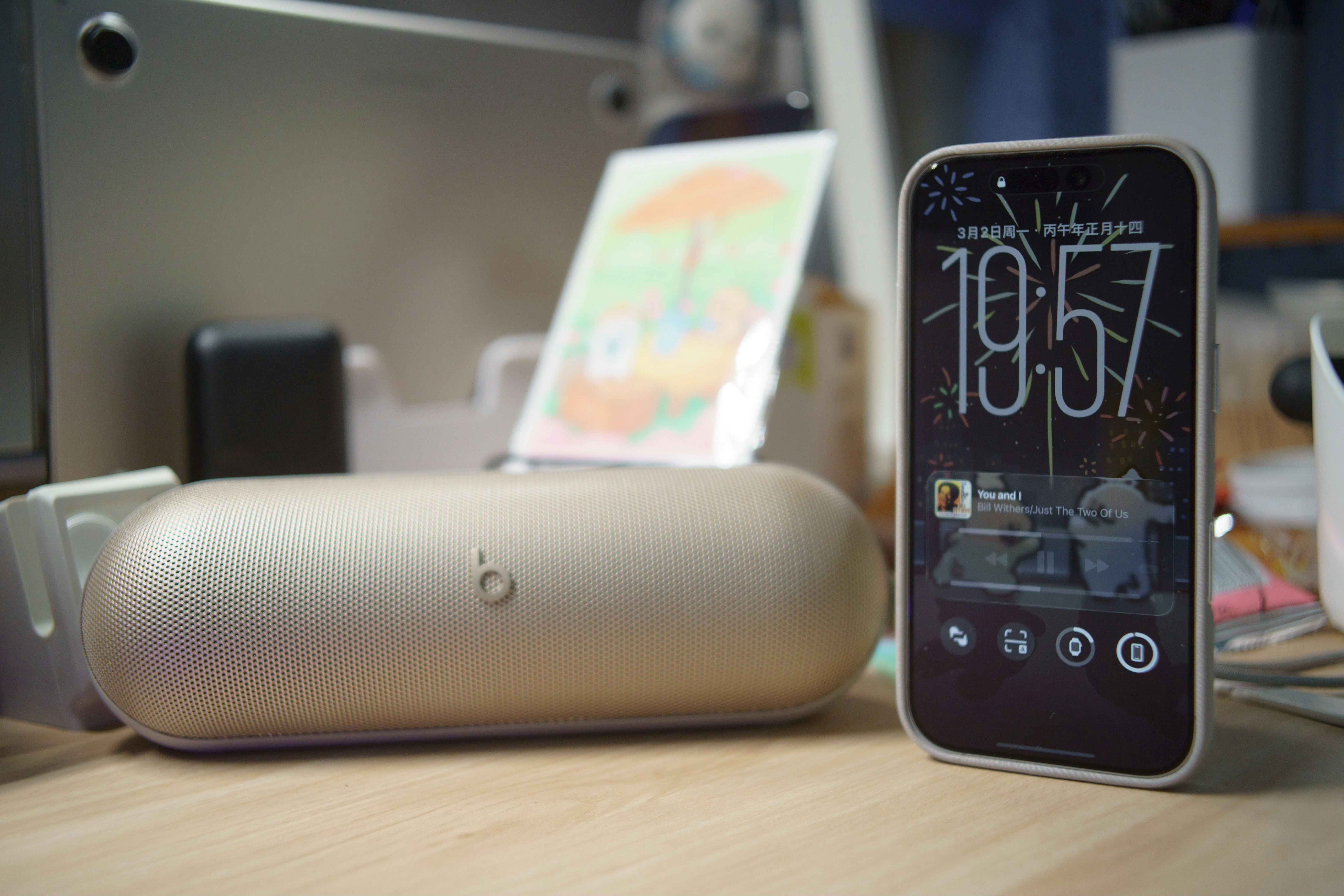 Smartphone and speaker on a wooden desk.