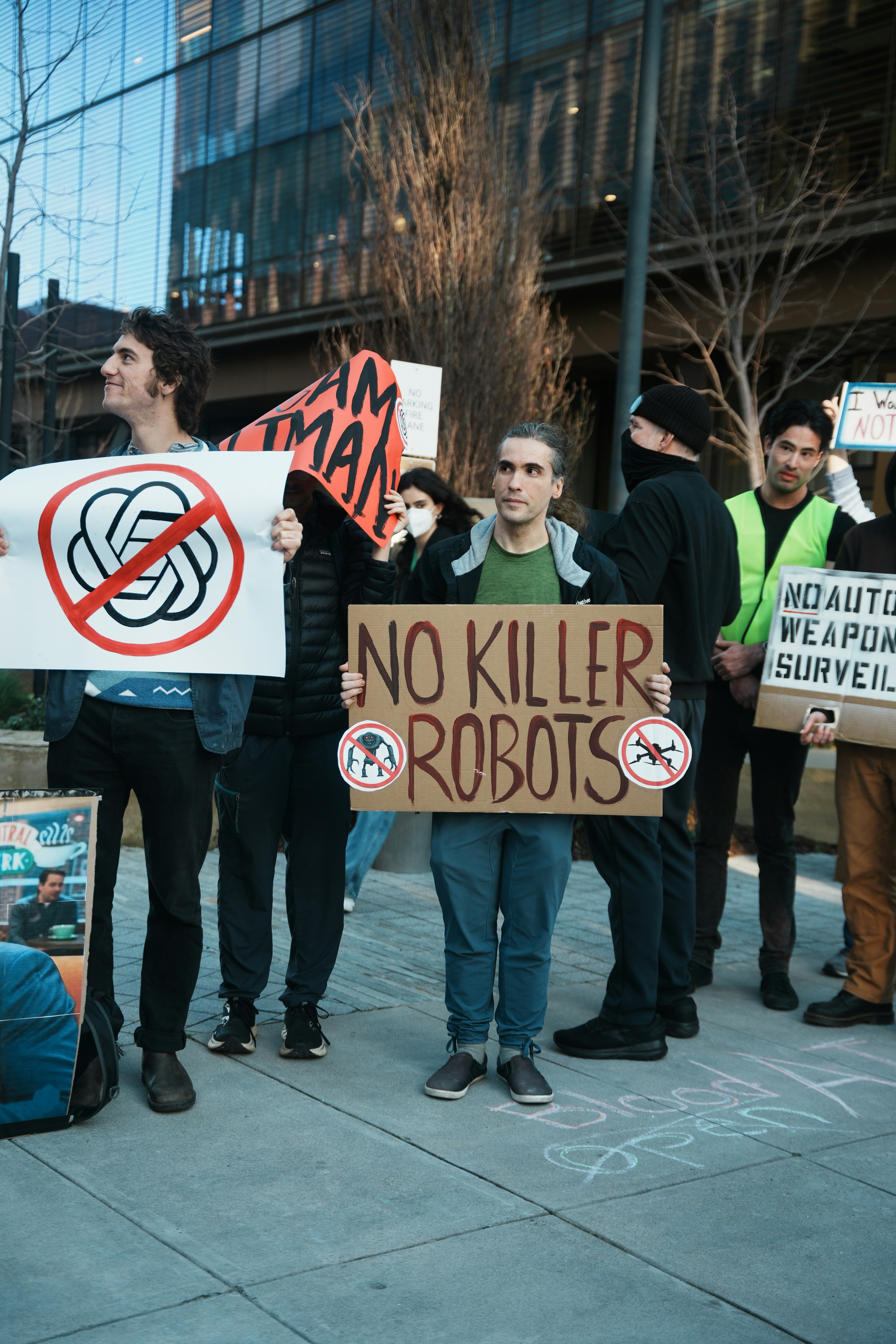 Protesters hold signs against killer robots and ai.