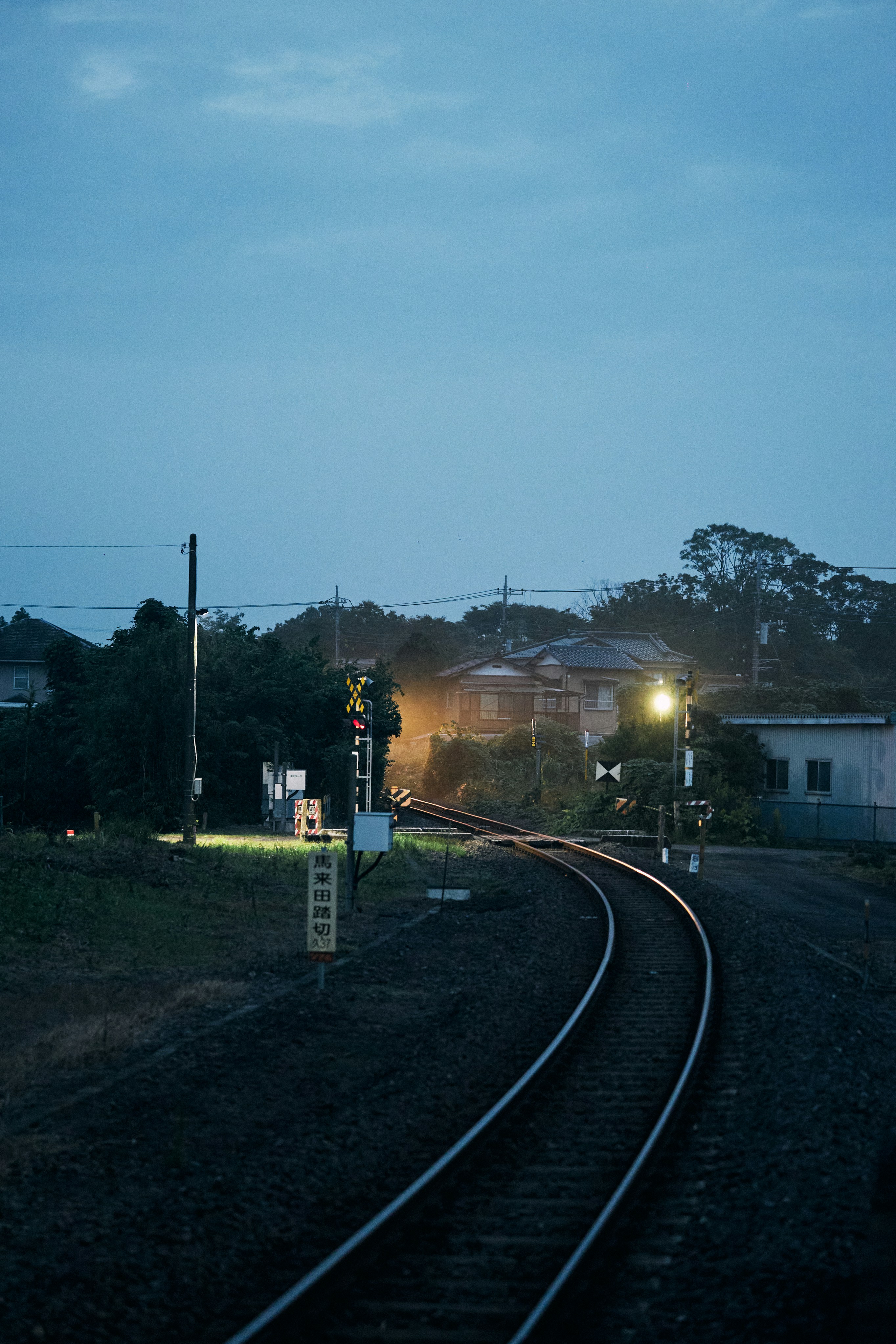 I binari del treno curvano attraverso un paesaggio rurale al crepuscolo.