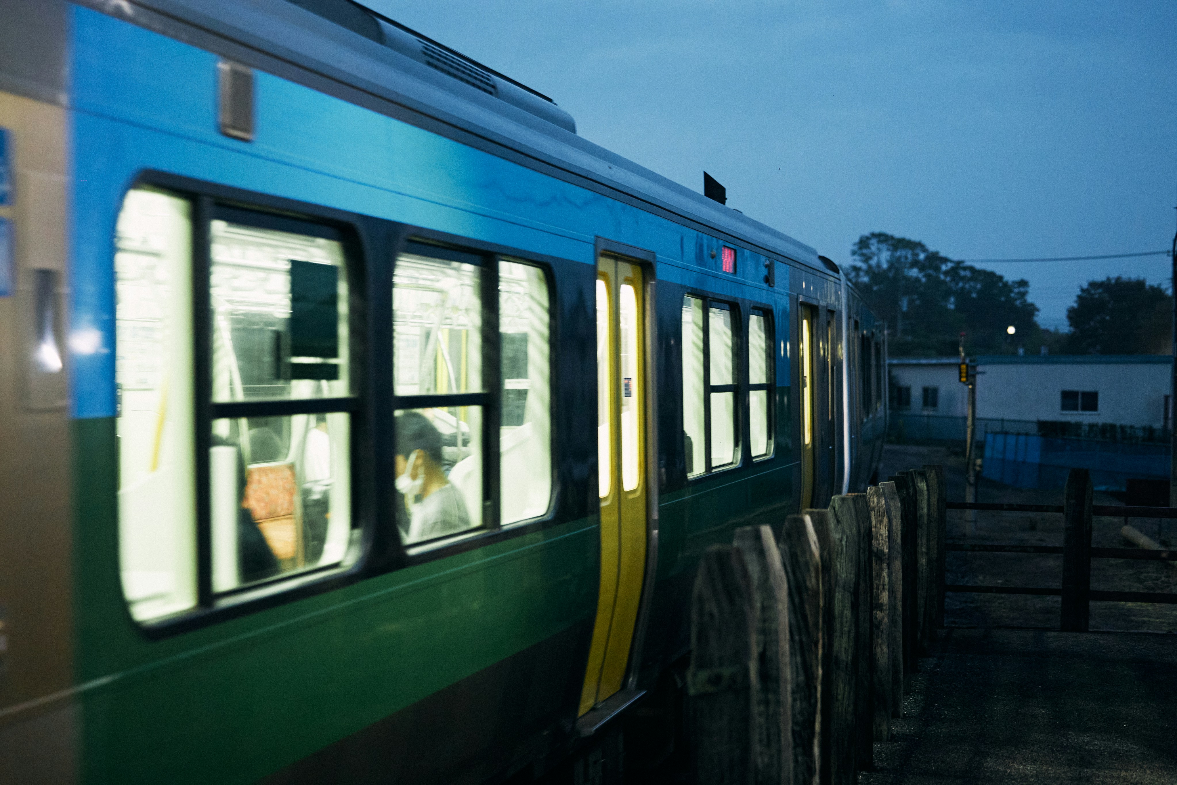 夕暮れ時に乗客が見える列車内部が照明に照らされる