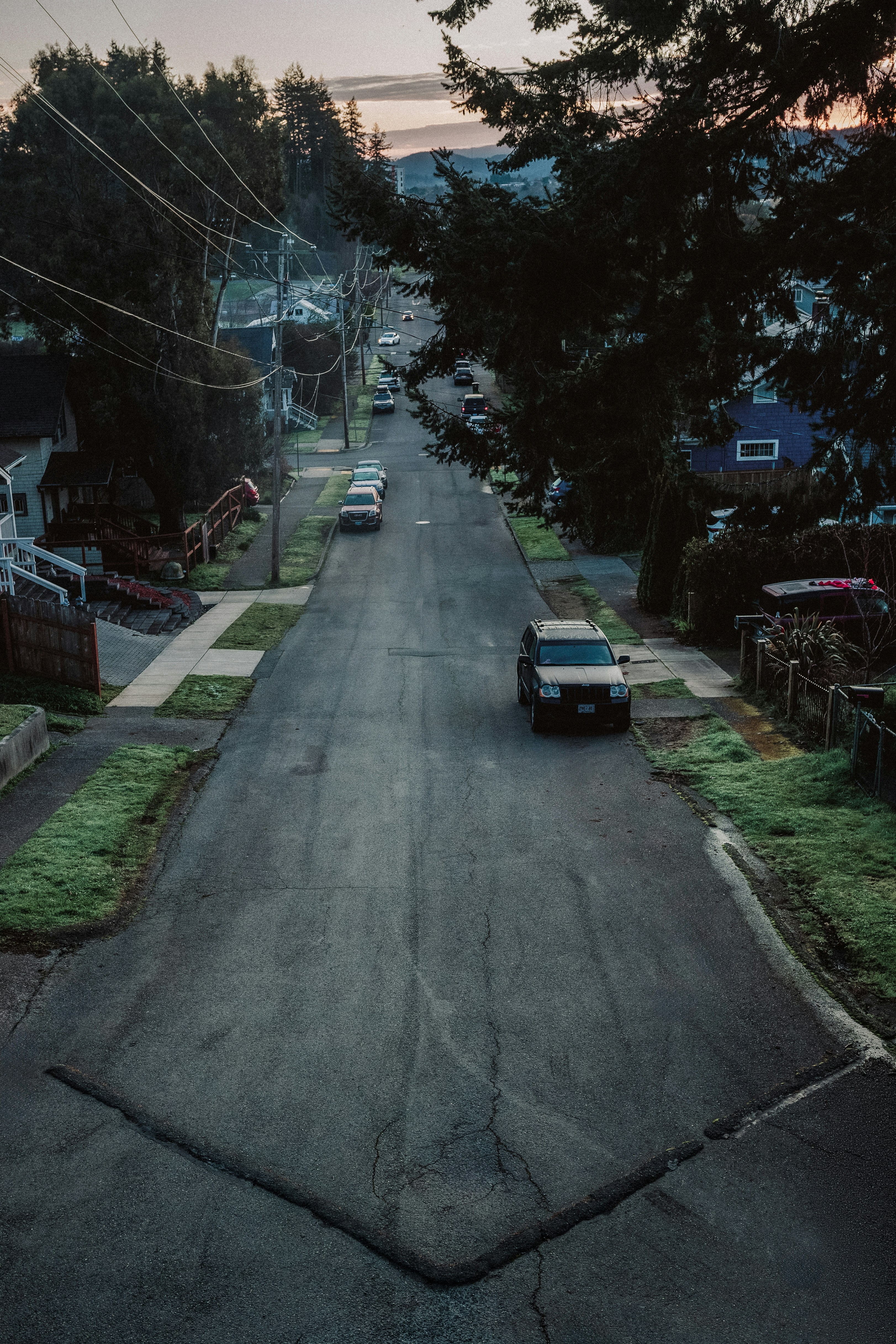 A suburban street with cars parked along the side.