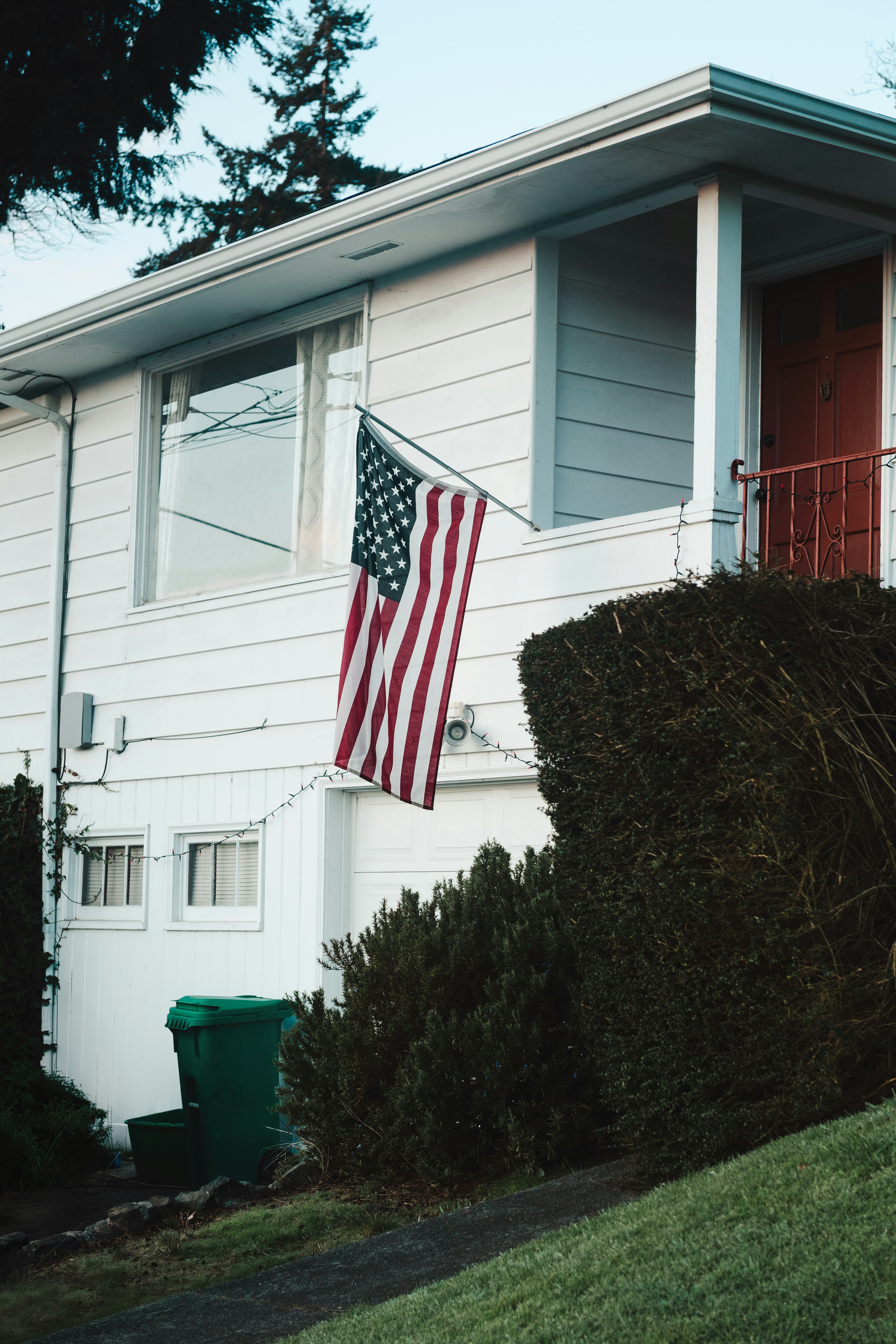 American flag hangs on a white house exterior.
