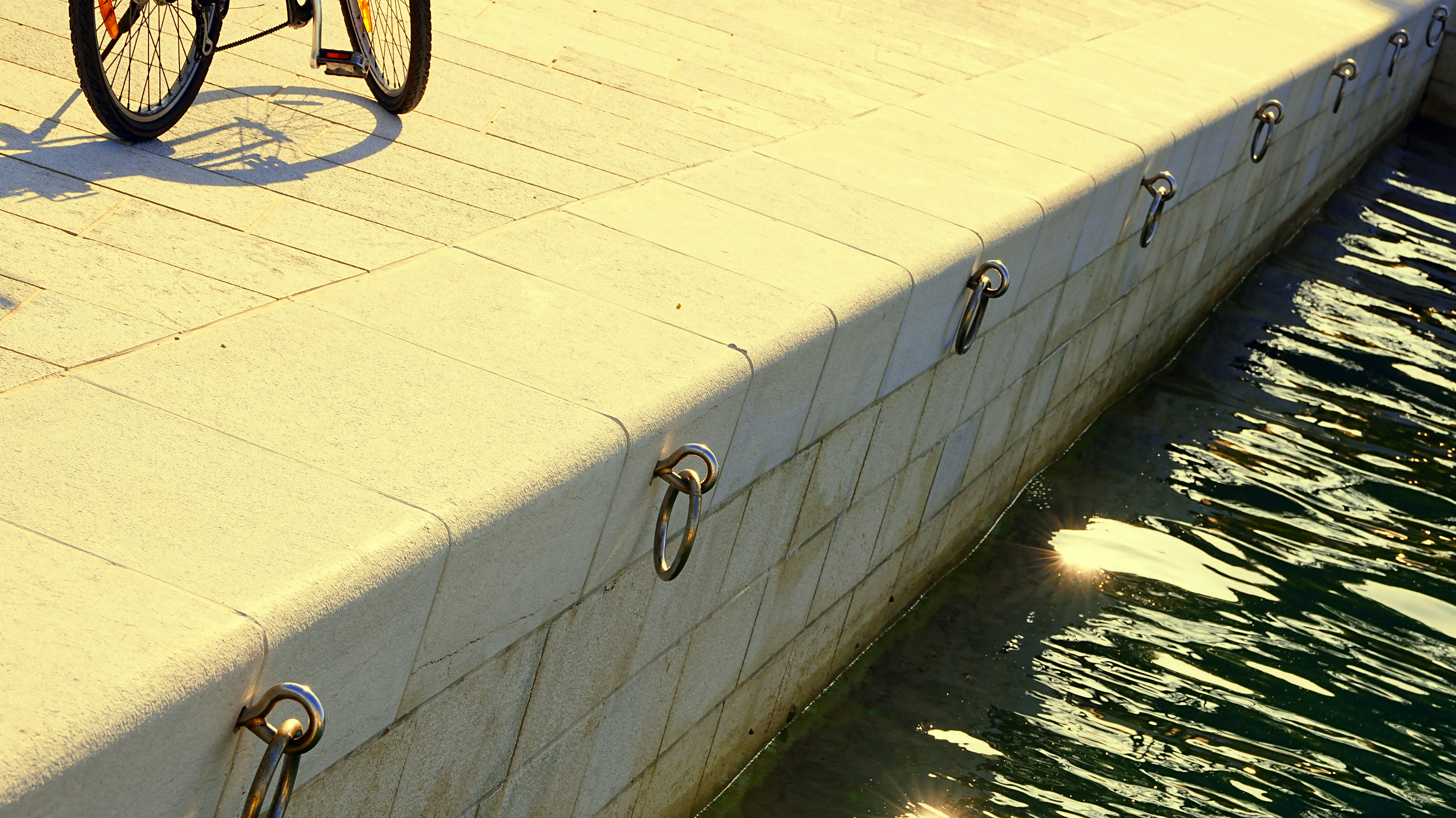 Ein Fahrrad, das auf einem sonnigen Steg am Wasser geparkt ist