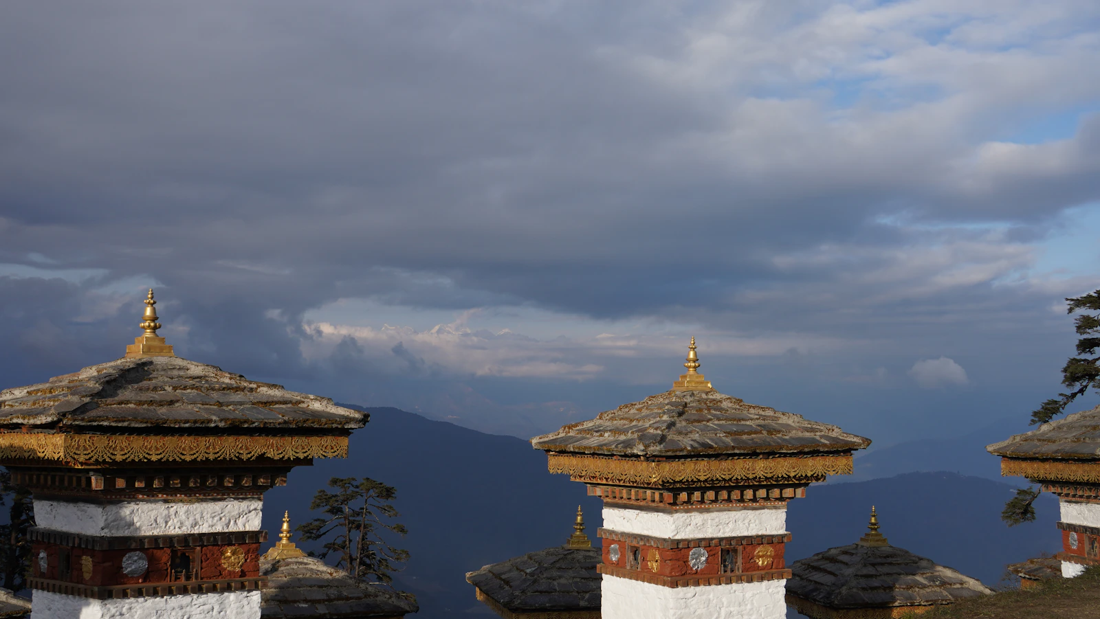 Gilded finials of the Dochu La chortens against evening cloud, blue ridges stretching away to the north
