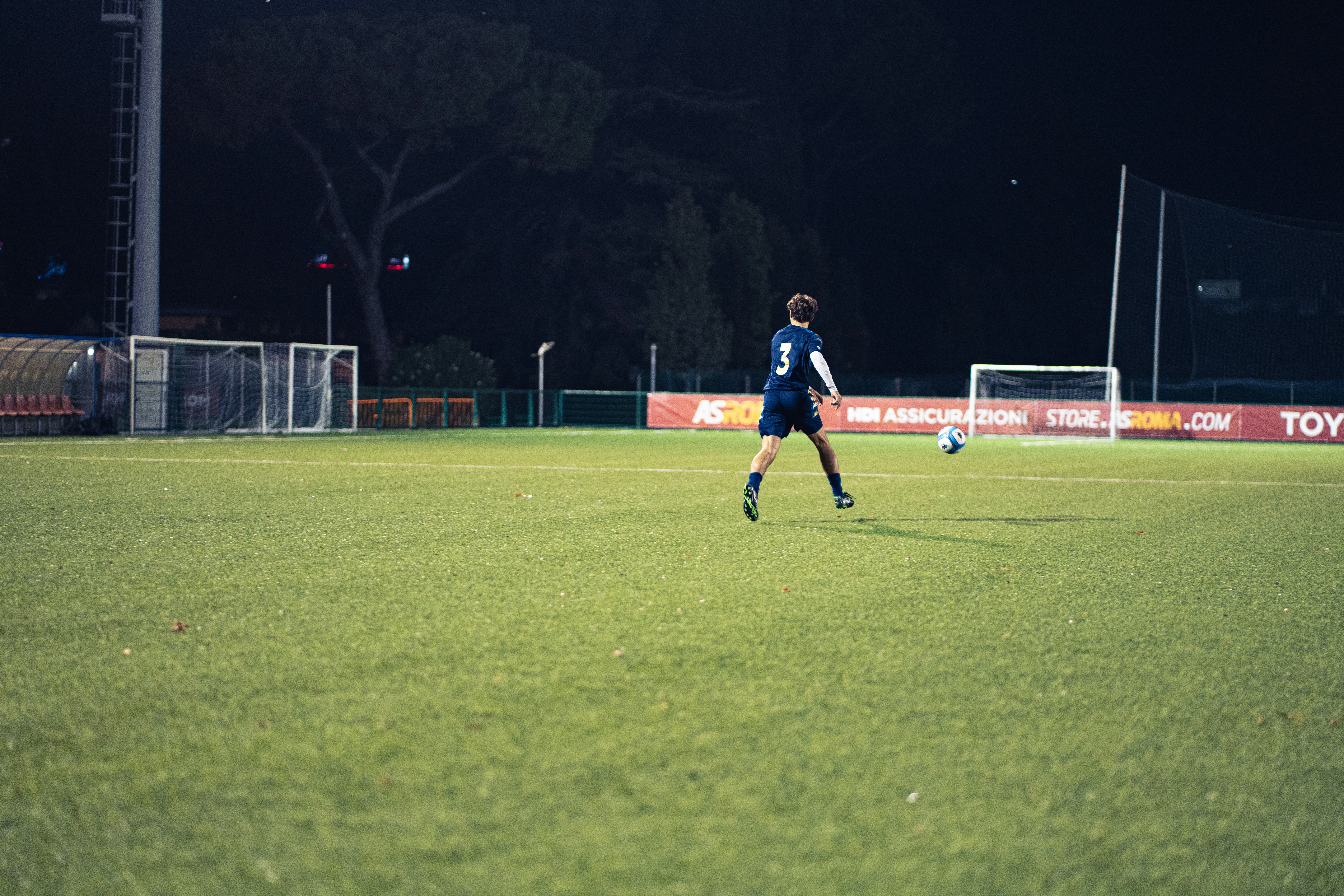 Estadio de fútbol iluminado de noche, tribunas con luces
