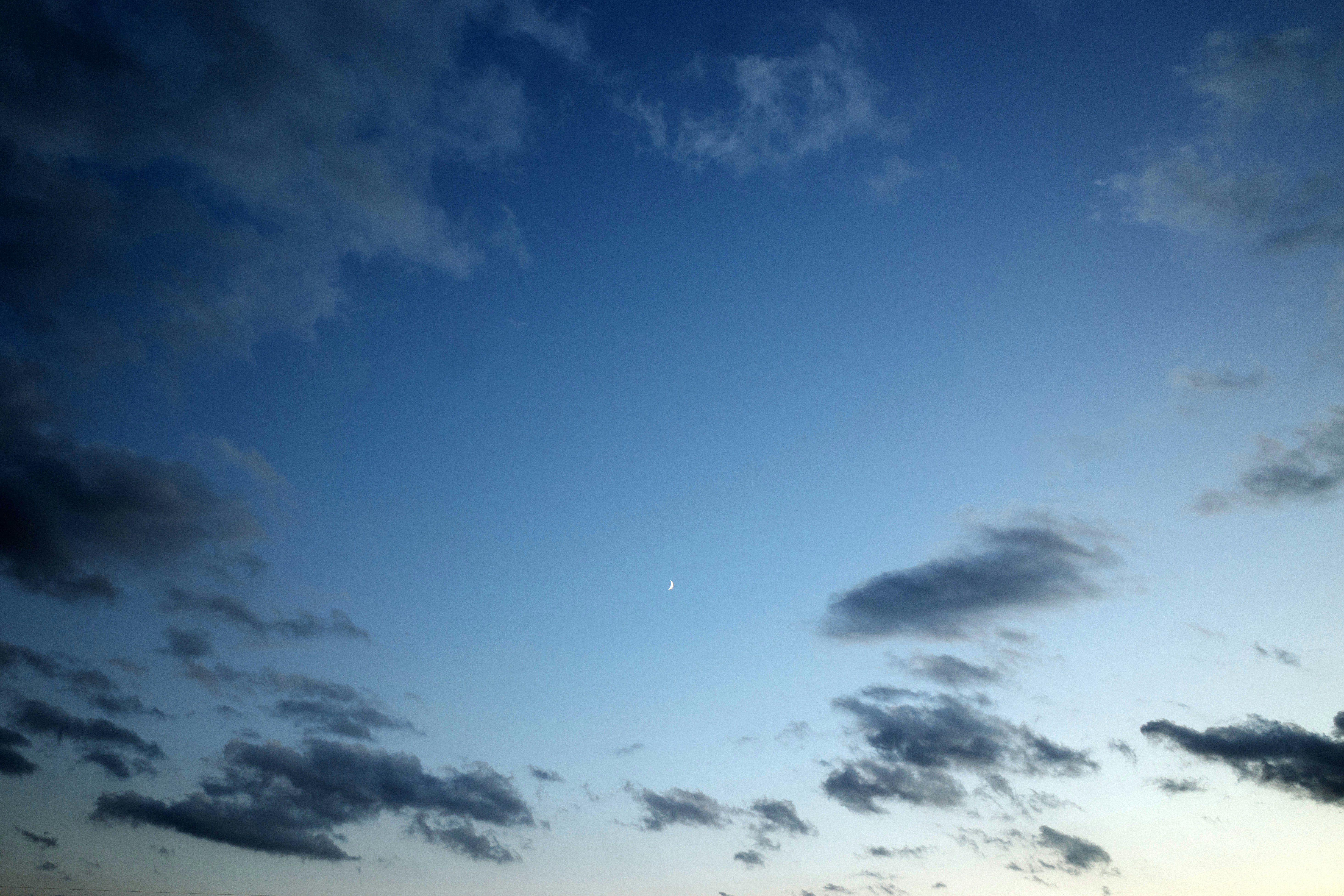 Una luna pallida pende nel cielo crepuscolo.